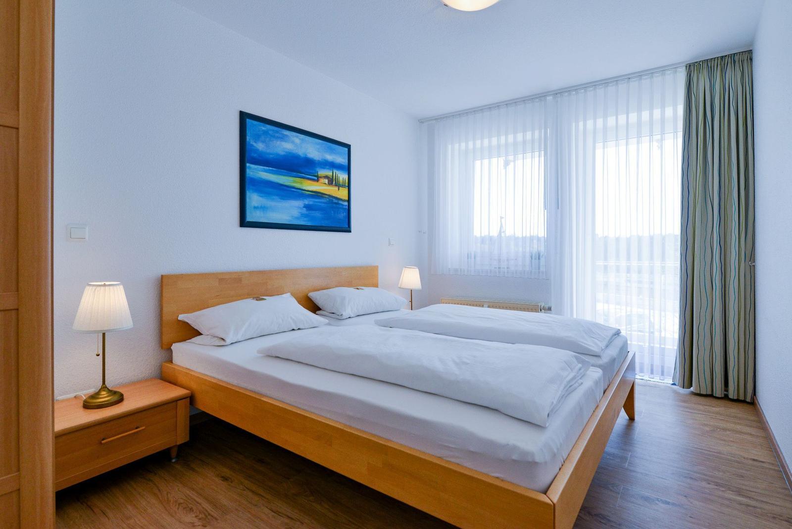 Ein Schlafzimmer mit Doppelbett, Holzmöbeln und einem Fenster mit Vorhängen.