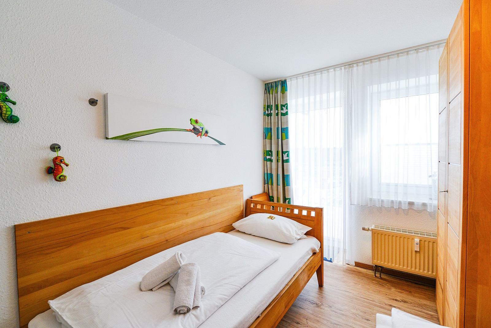 Ein Schlafzimmer mit Holzbett, Fenster mit Vorhängen und Wanddekoration.