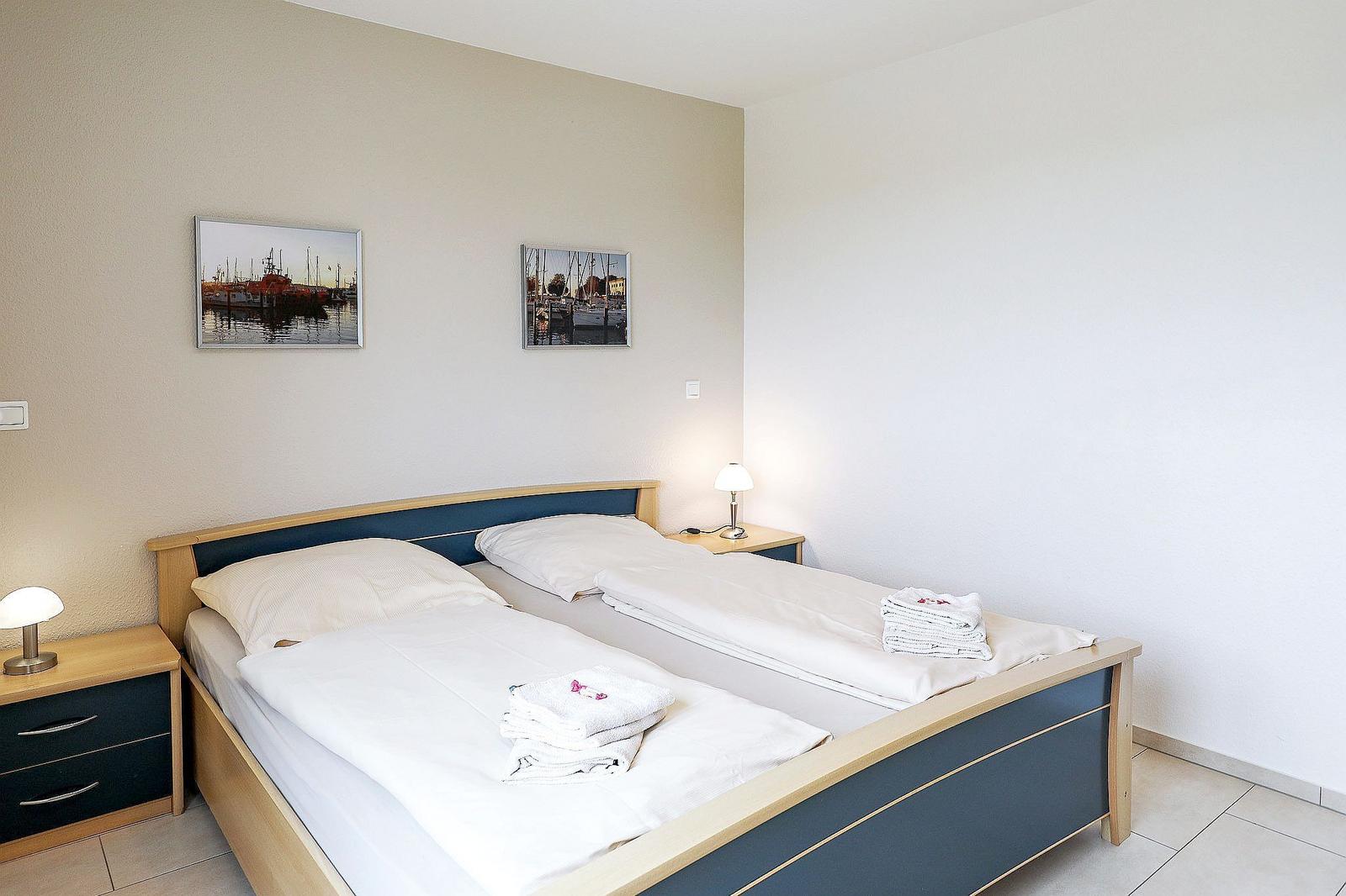 Schlafzimmer mit Doppelbett, zwei Nachttischen und Bildern an der Wand.