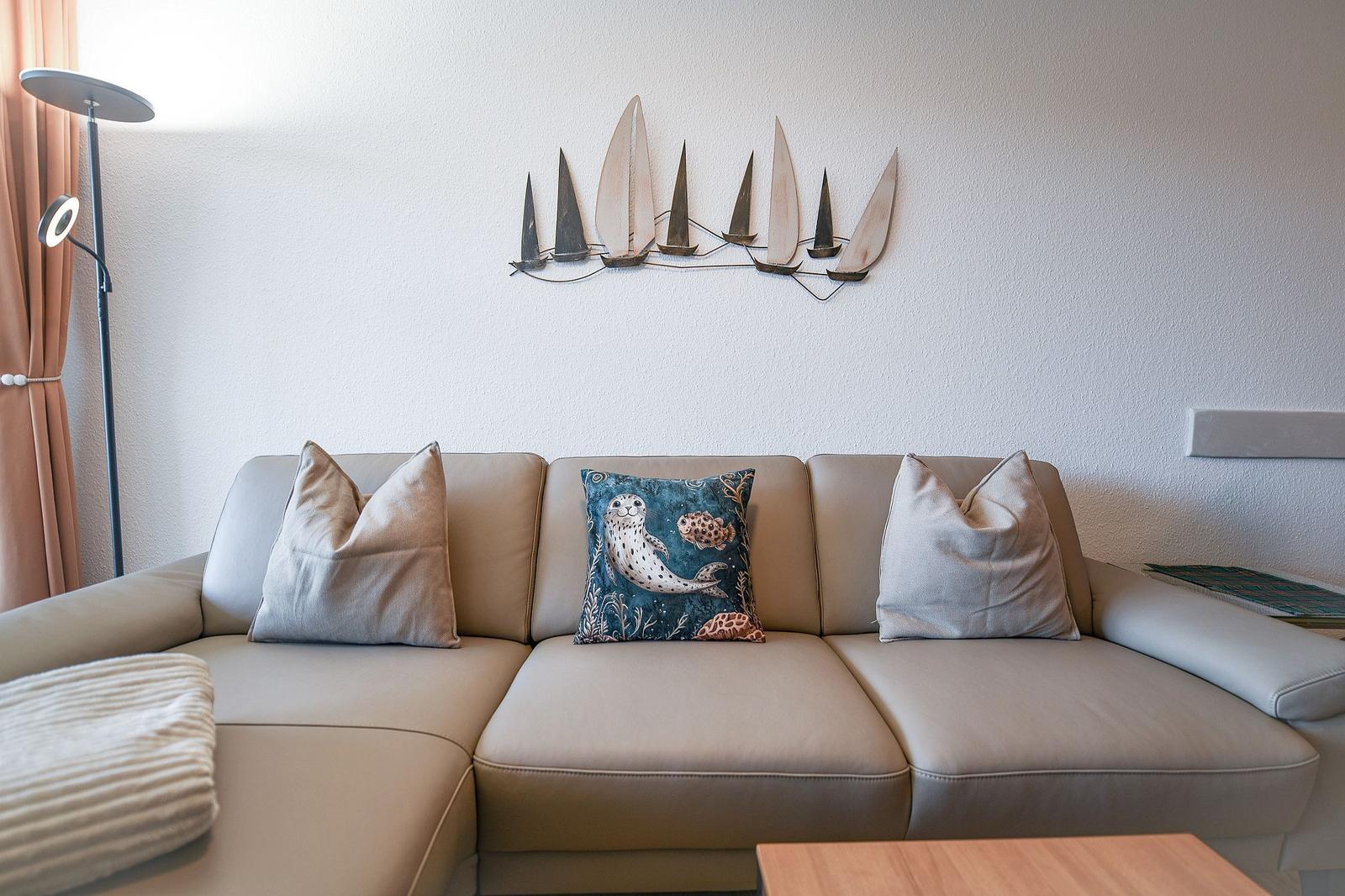Ein Sofa mit Kissen und Wanddekoration mit Segelbooten.