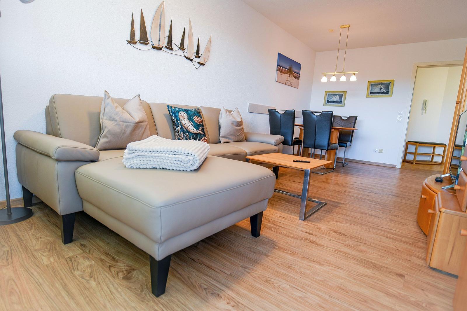 Wohn- und Essbereich mit Sofa, Tisch und Stühlen auf Holzboden.