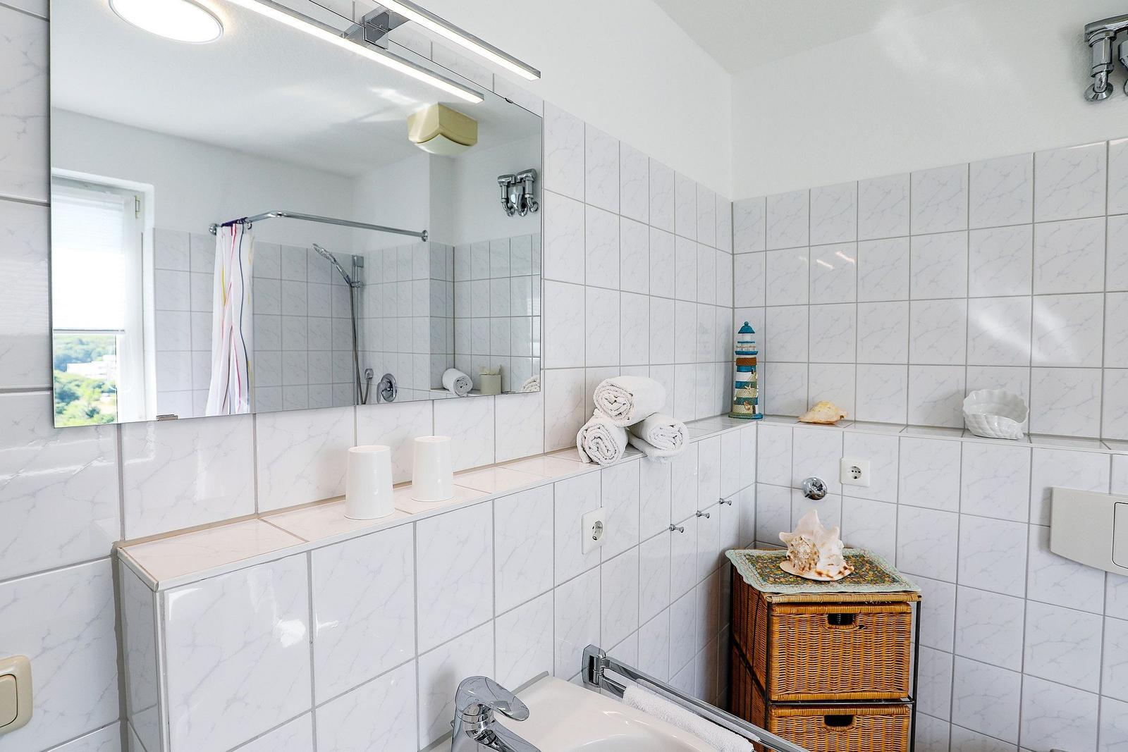 Bathroom with mirror, shower, sink, and towels.