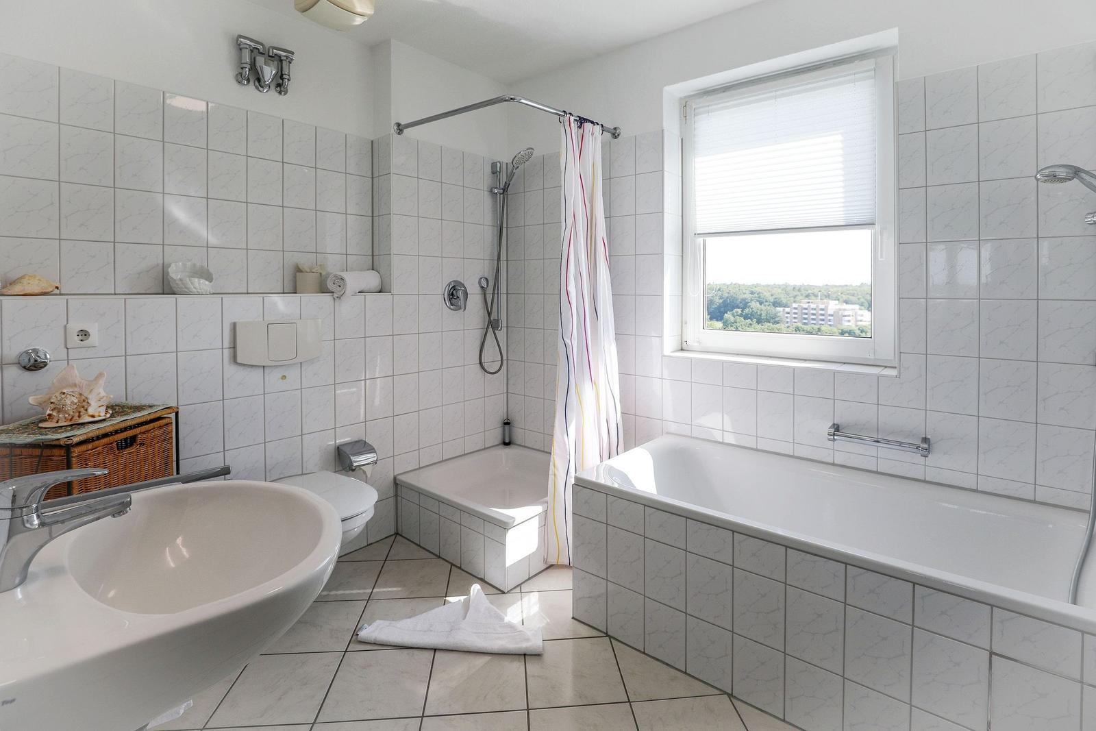 Bathroom with bathtub, shower, and window with view.