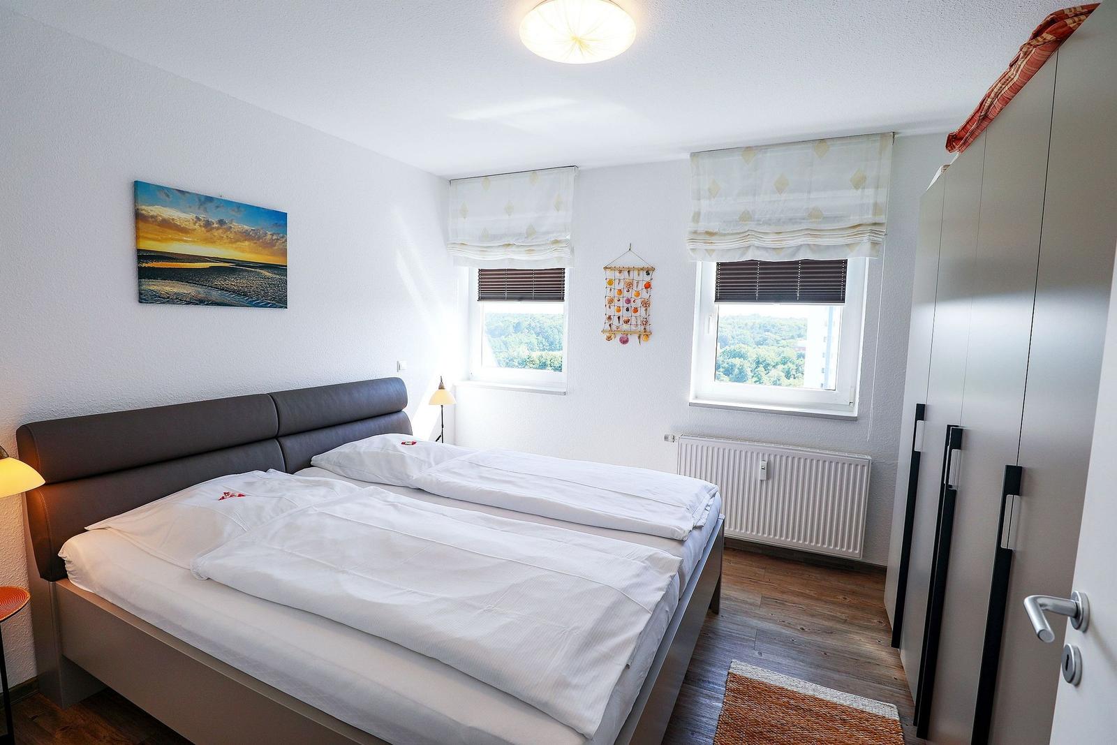 Bedroom with double bed, two windows, and wardrobe.