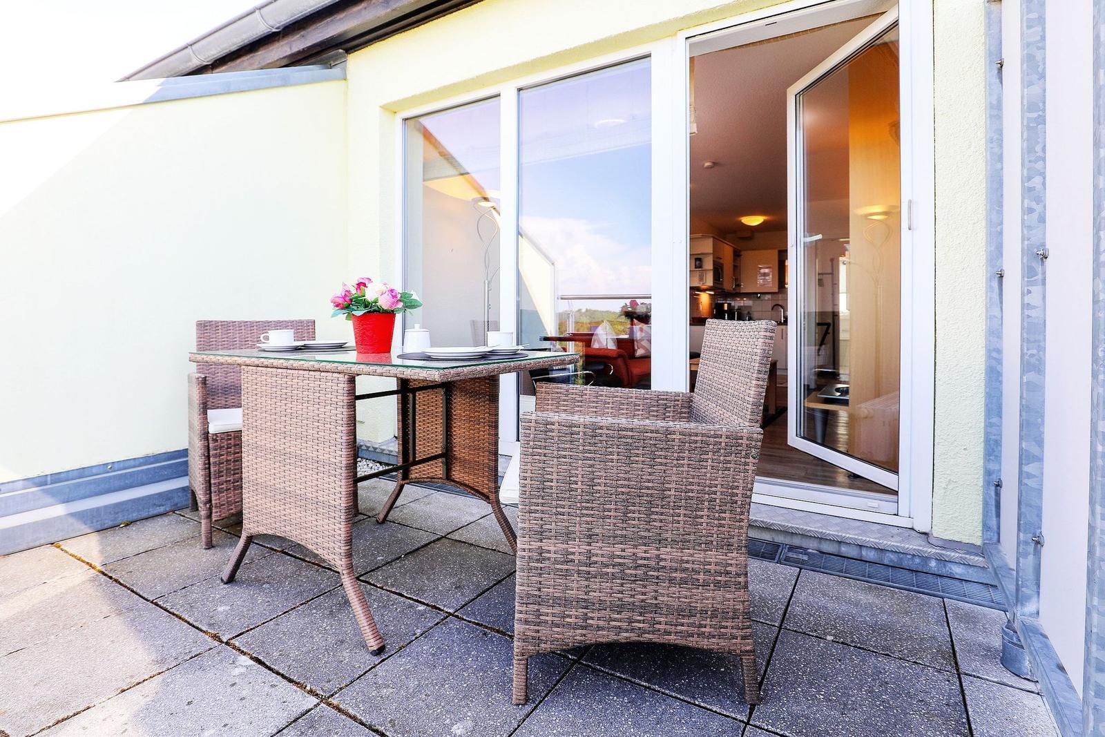 Terrace with table and chairs, view into the apartment.