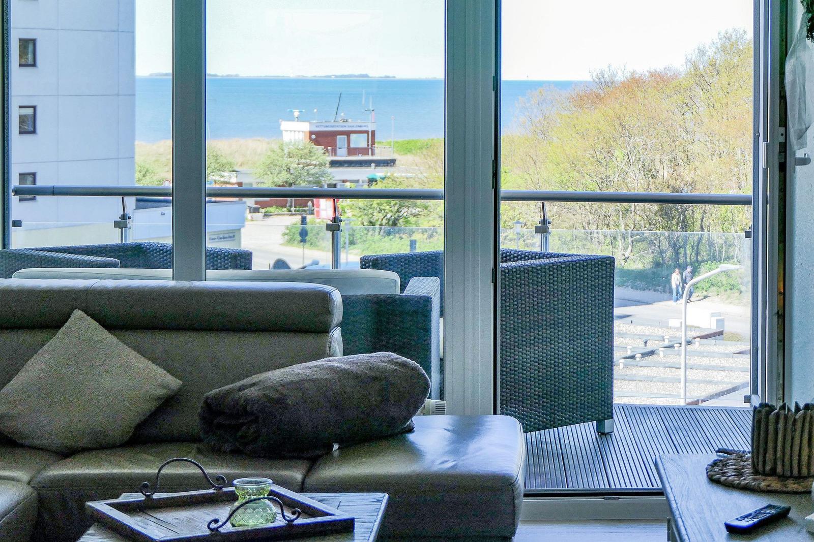 Ein Wohnzimmer mit Blick auf See und Balkon mit Sitzmöbeln.