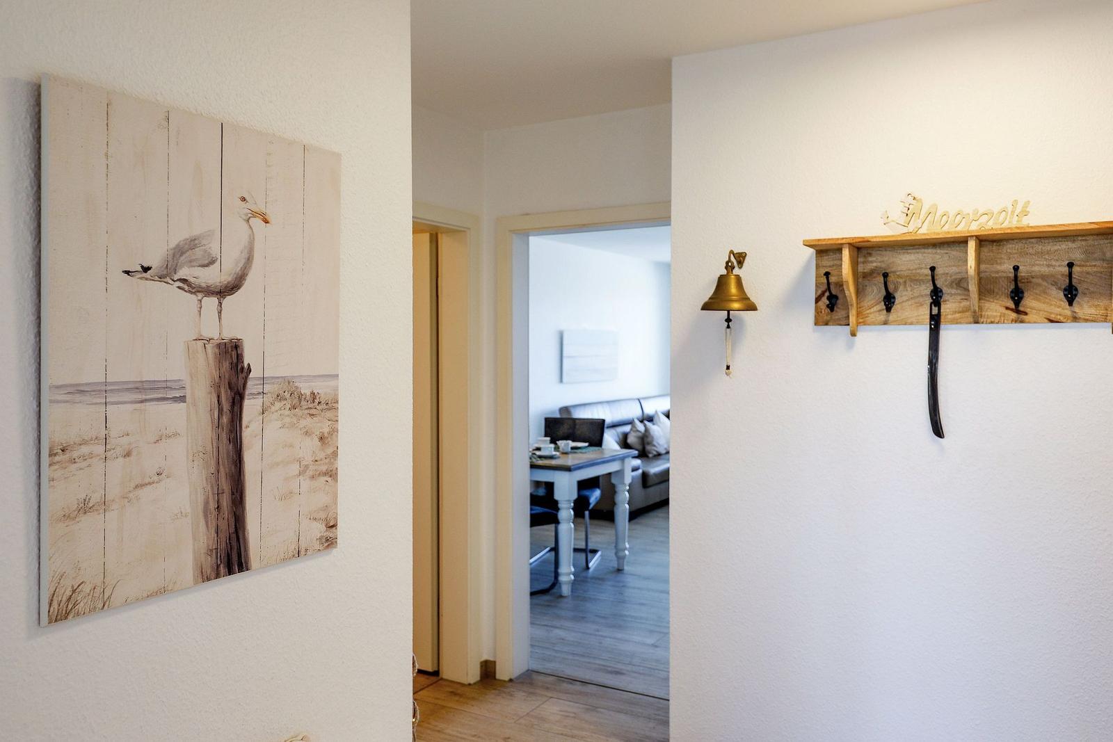 Hausflur mit Wandbild, Garderobe und Blick in Wohnzimmer.