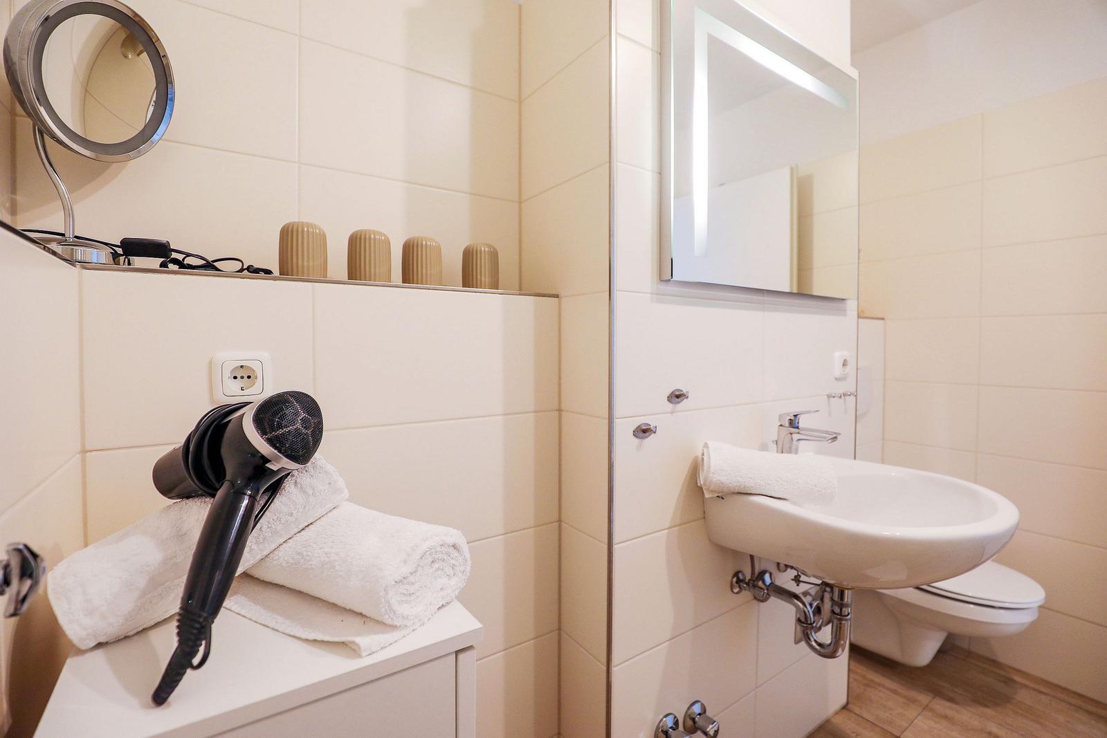 Badezimmer mit Waschbecken, Toilette, Spiegel und Handtuch