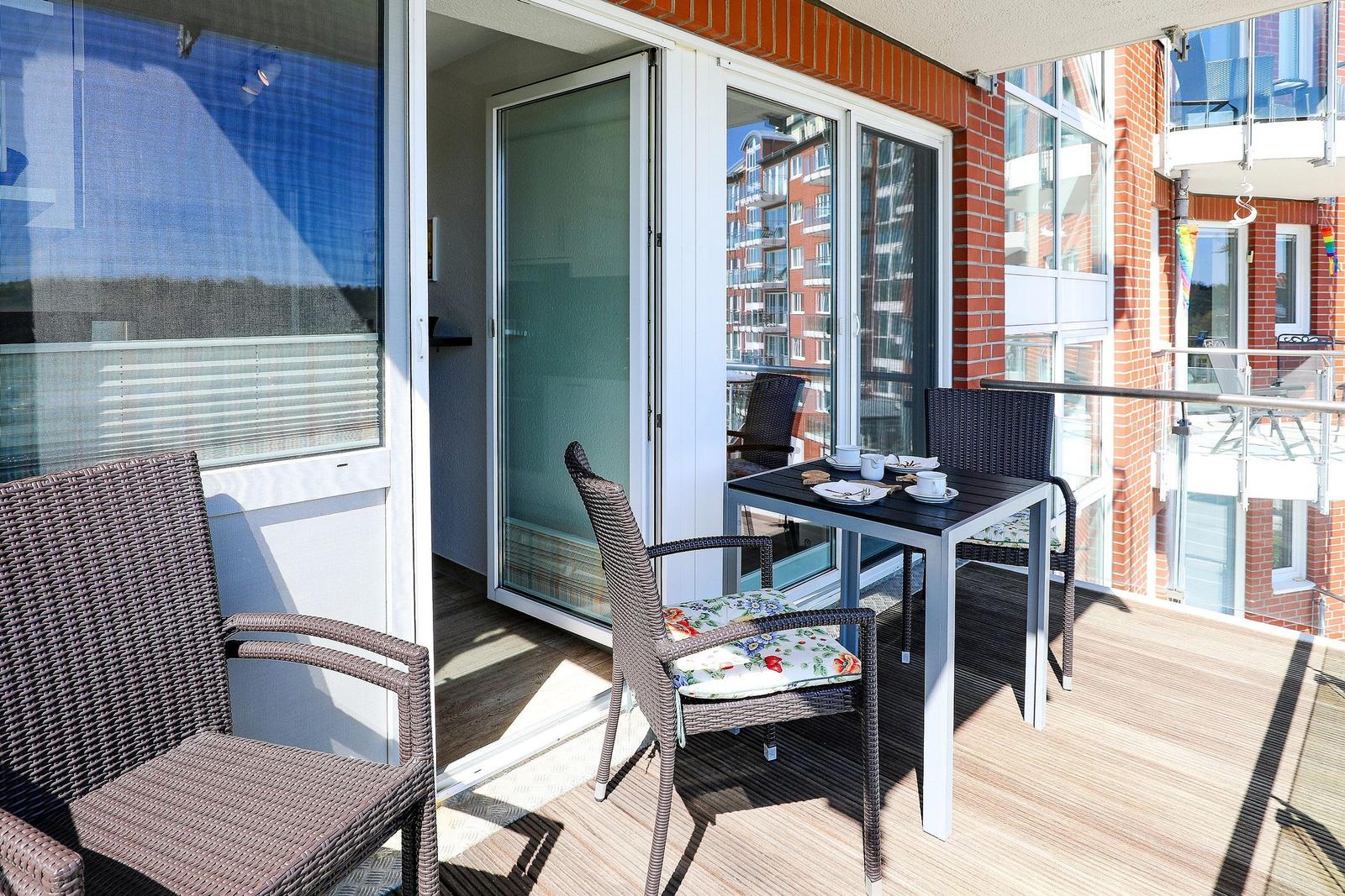 Terrasse mit Tisch, Stühlen und Sicht auf Gebäude.
