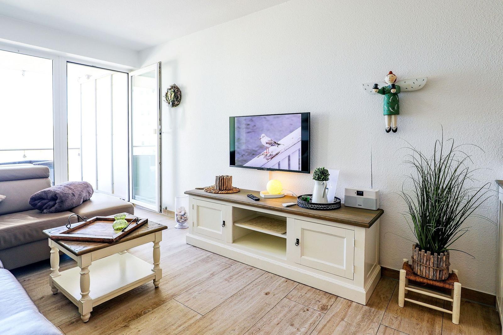 Wohnzimmer mit Fernseher, Couch und Terrassentür.