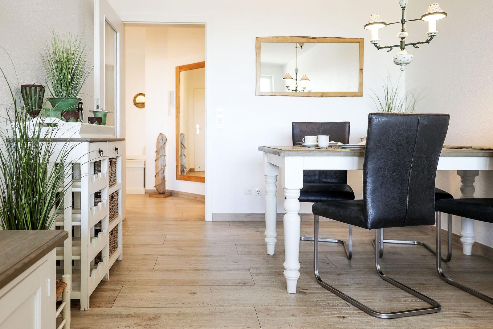 Essbereich mit Tisch, Stühlen und Spiegel an der Wand.