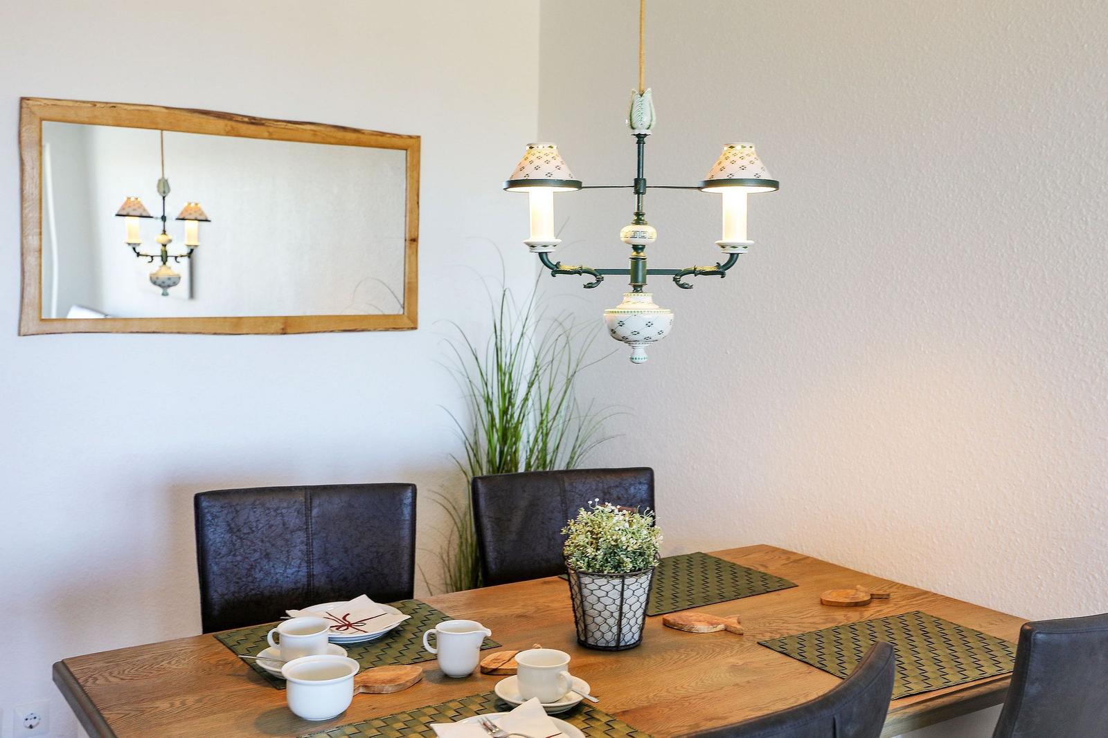 Esstisch mit Stühlen, Deckenleuchte und Spiegel an der Wand.