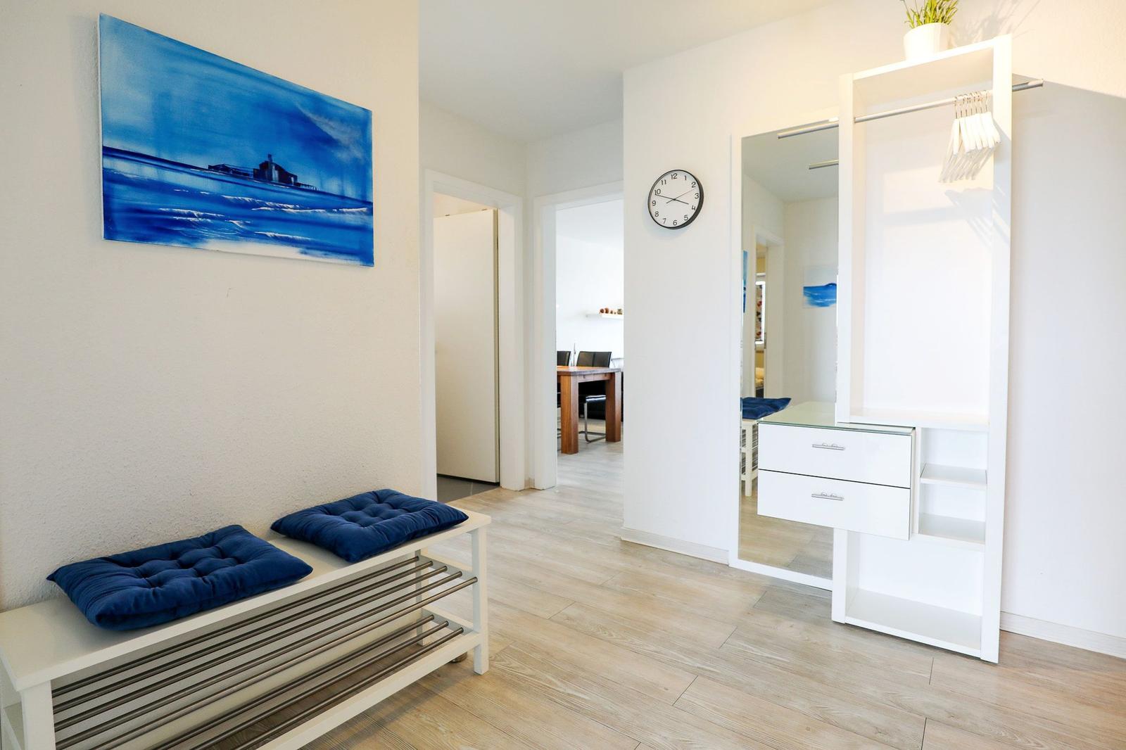 Eingangsbereich mit Sitzbank, Wandbild und Kleiderschrank. Durchgang zu Küche und Wohnzimmer.