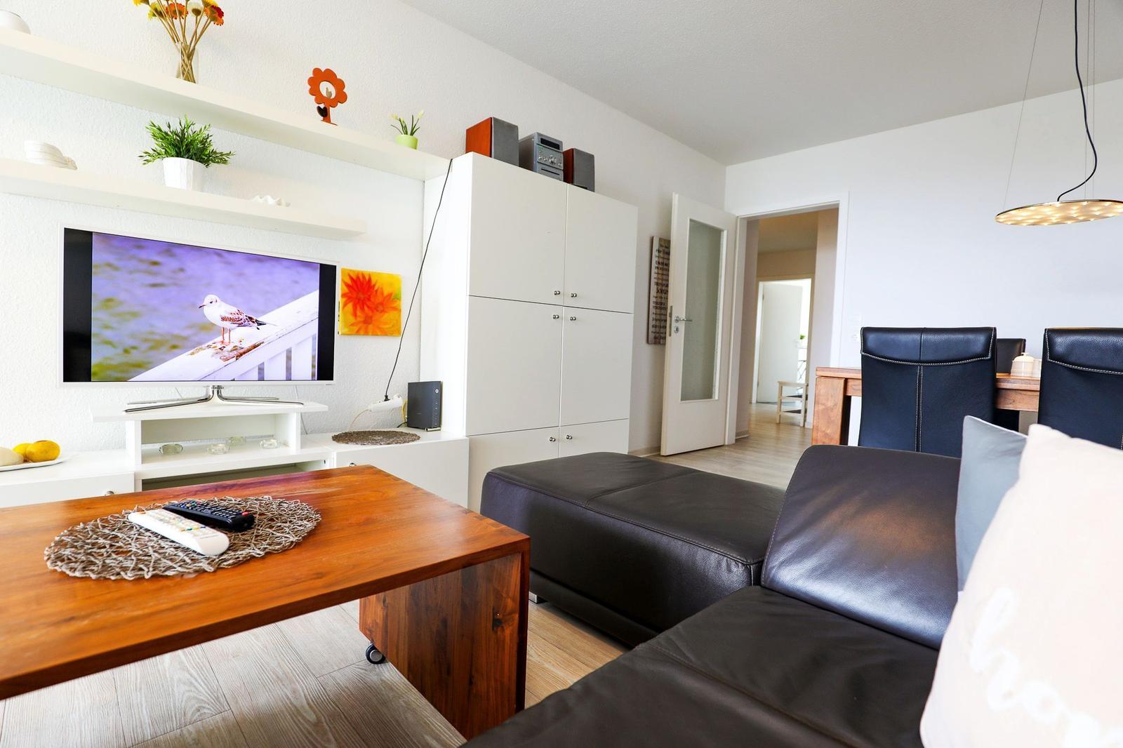 Wohnzimmer mit Sofa, Fernseher und Holztisch