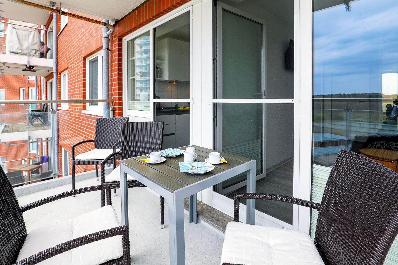 Terrasse mit Tisch und Stühlen, Blick auf Wohnbereich und Außenbereich.