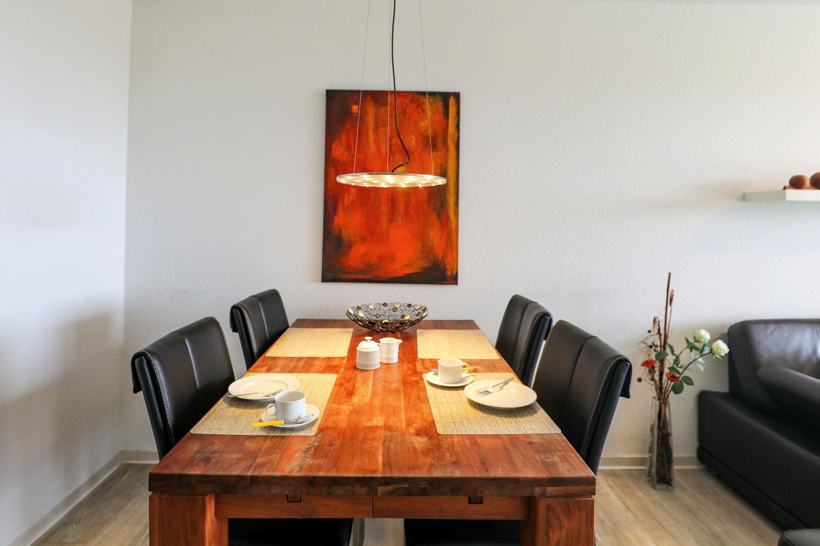 Esstisch mit sechs Stühlen, Wandbild und Deckenleuchte