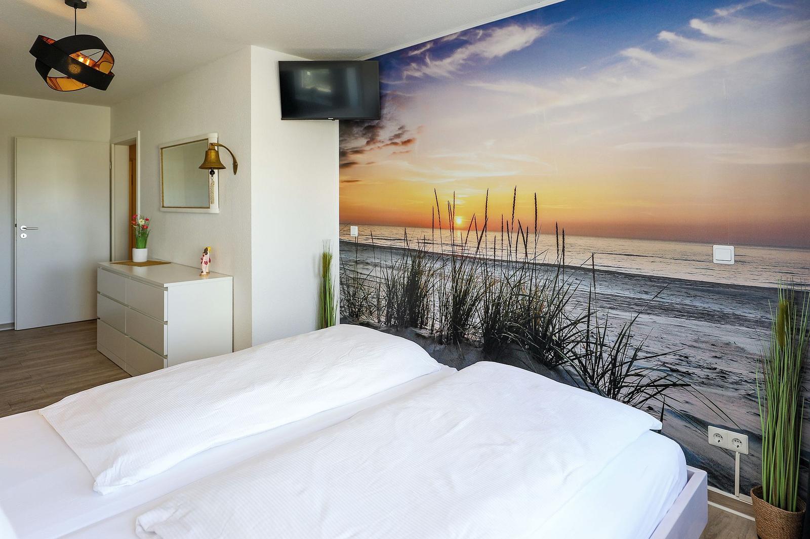 Schlafzimmer mit Bett, Wandbild Strand und TV