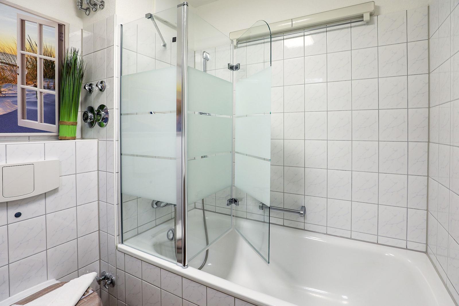 Bad mit Dusche und Badewanne, Wandfliesen und Fenster mit Blick.