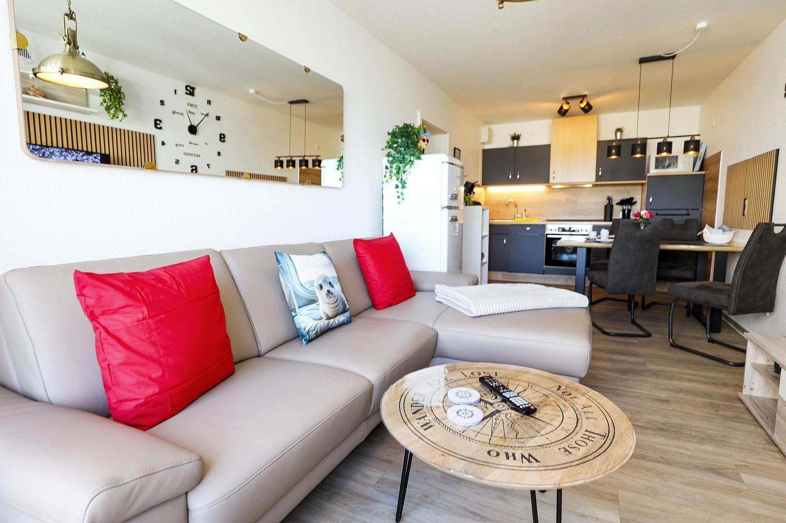 Wohnbereich mit Sofa, Couchtisch und Küchenbereich im Hintergrund.