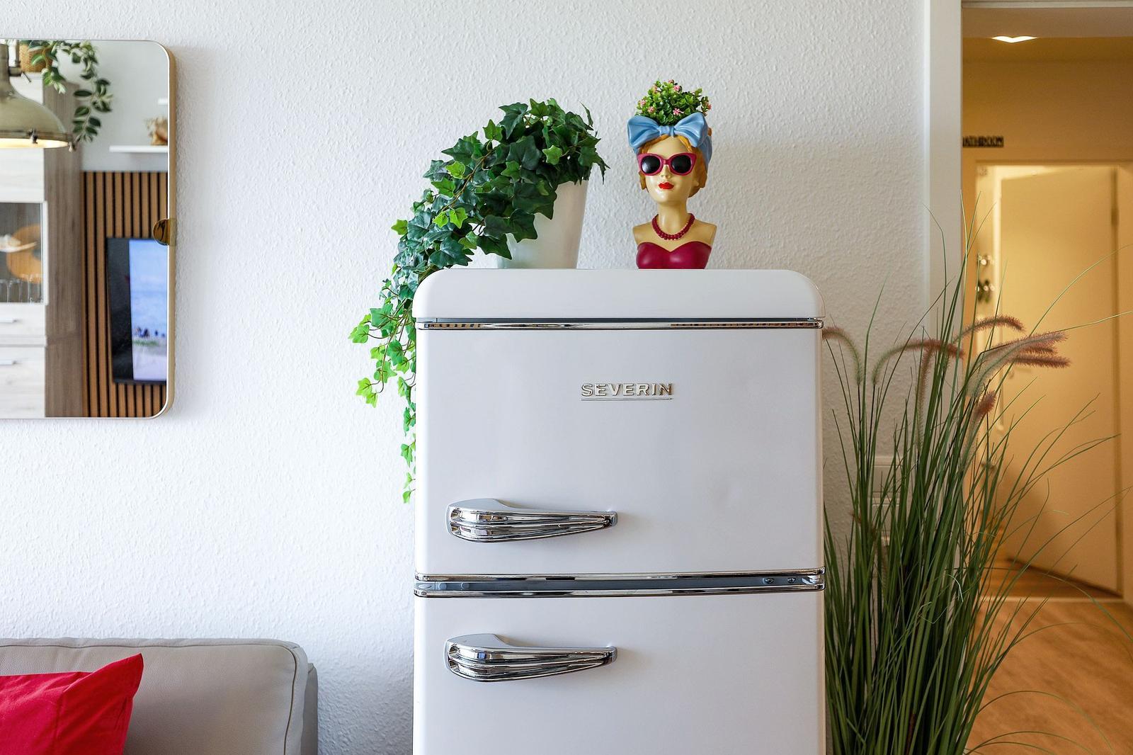 Weißer Kühlschrank mit Dekoration und Pflanzen im Raum