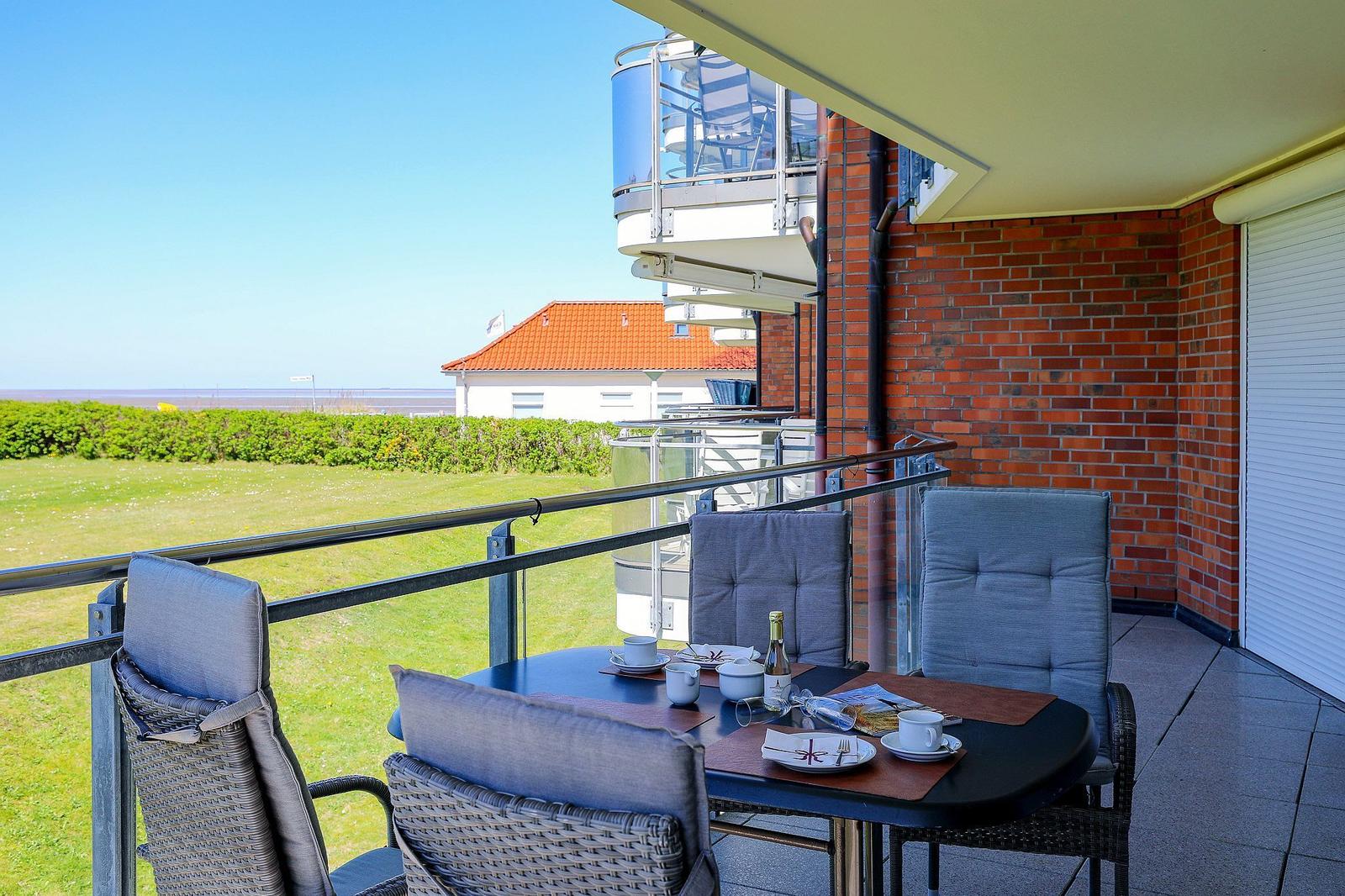 Terrasse mit Tisch und Stühlen, Blick auf Grünfläche und Haus.