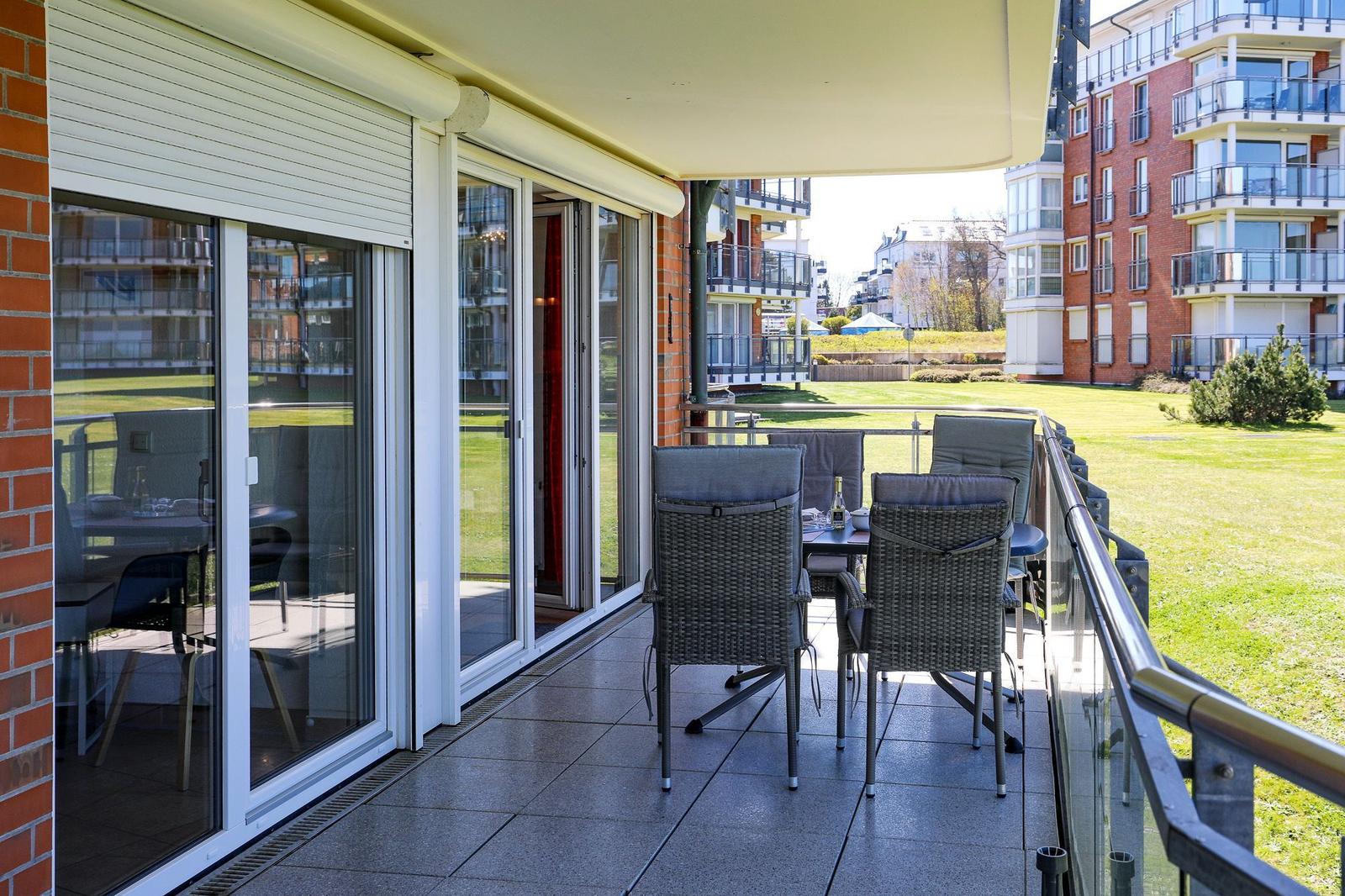 Terrasse mit Tisch und Stühlen, Blick auf grünen Rasen und Wohnhäuser.