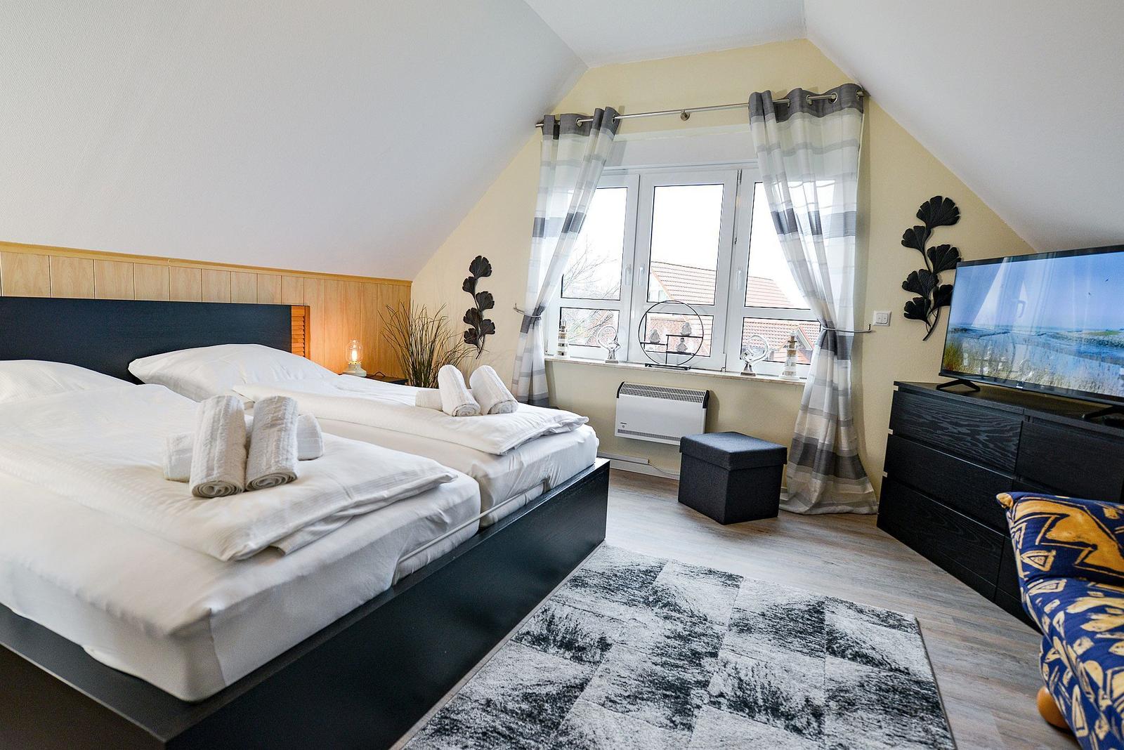 Zimmer mit Doppelbett, TV und Fenster mit Blick auf Dächer.