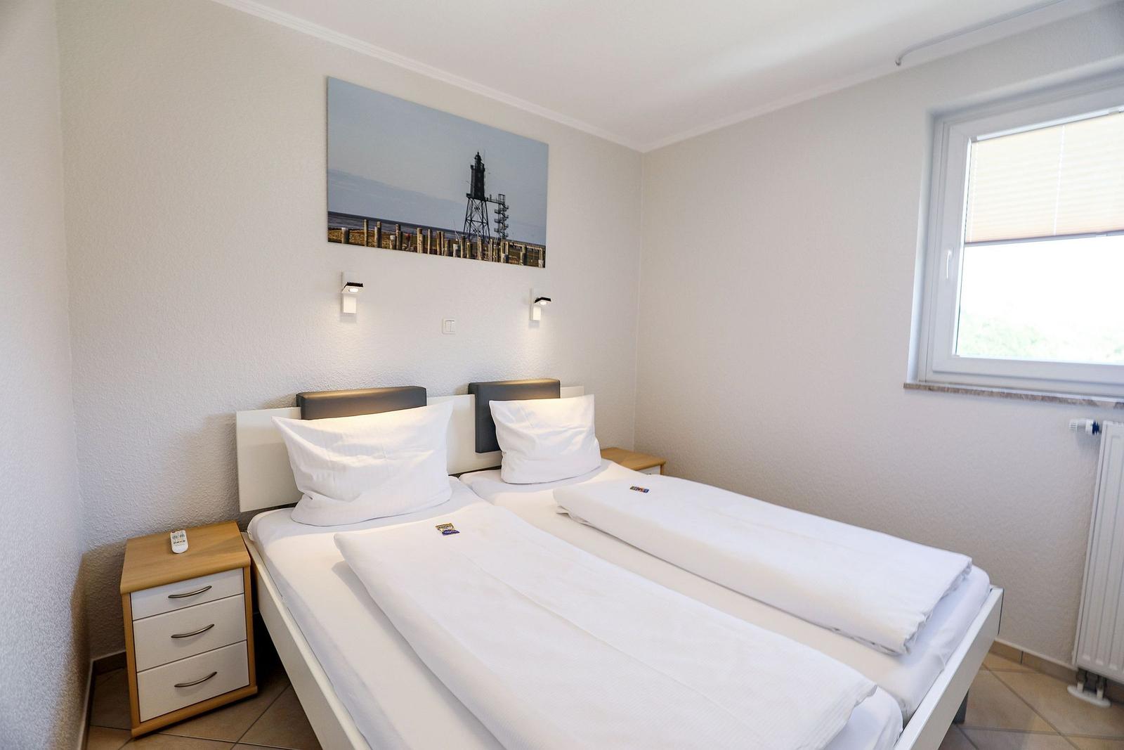 Schlafzimmer mit Doppelbett, Nachttisch und Wandbild.
