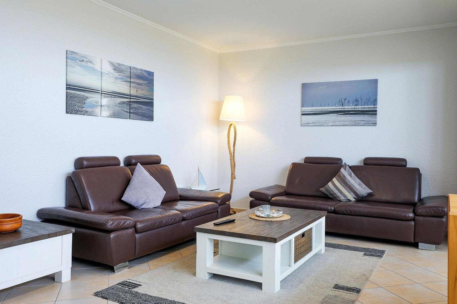 Wohnzimmer mit zwei braunen Sofas, Tisch und Wandbildern.