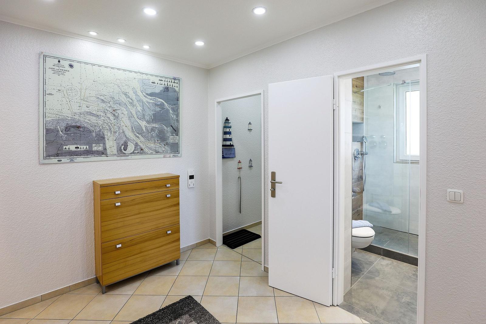 Flur mit Holzschrank, Seekarte an der Wand und Blick in Bad und Dusche.