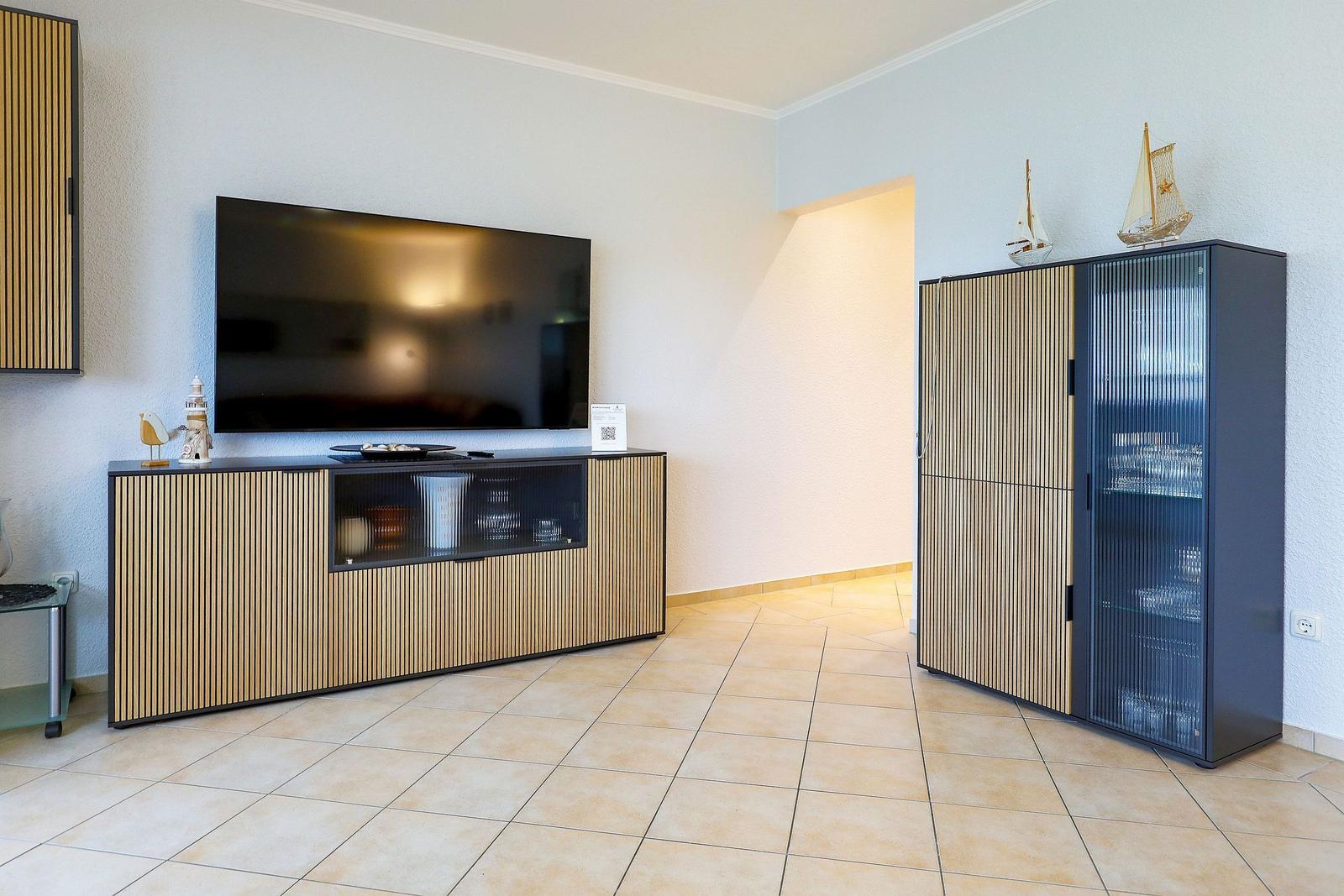 Wohnzimmer mit TV, Sideboard und Glasvitrine. Holz- und Glasfronten.