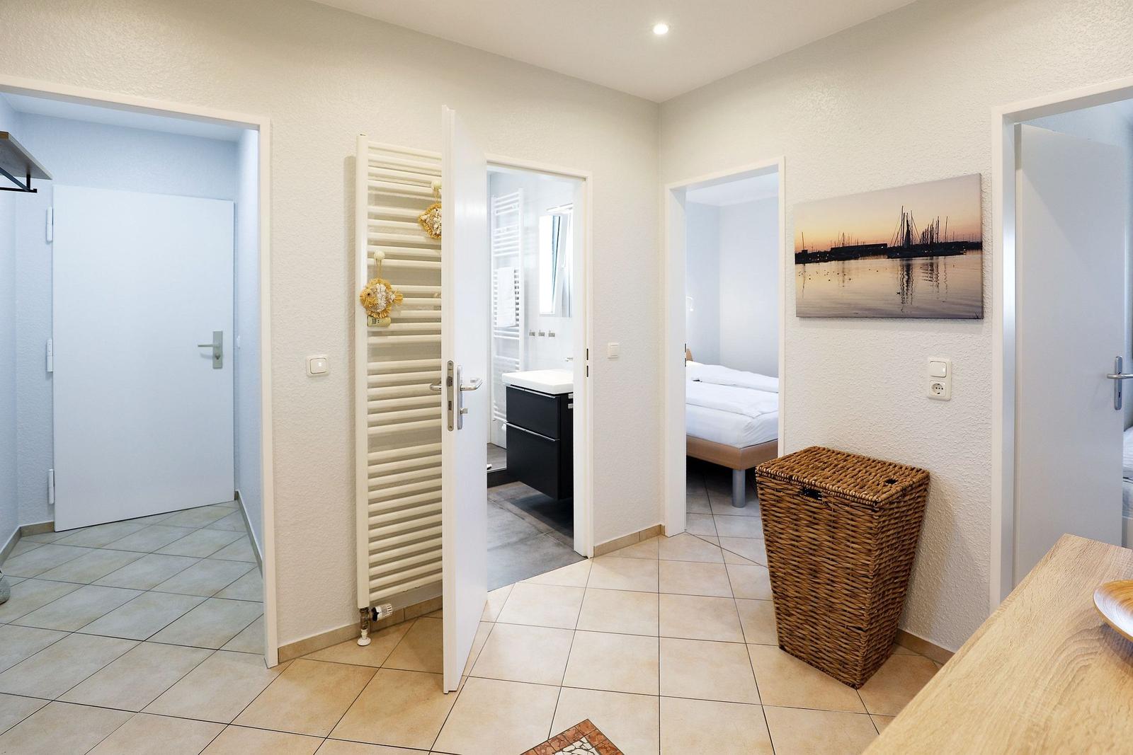 Flur mit Tür zu Bad, Schlafzimmer und Garderobe. Wandbild und Korb sind sichtbar.