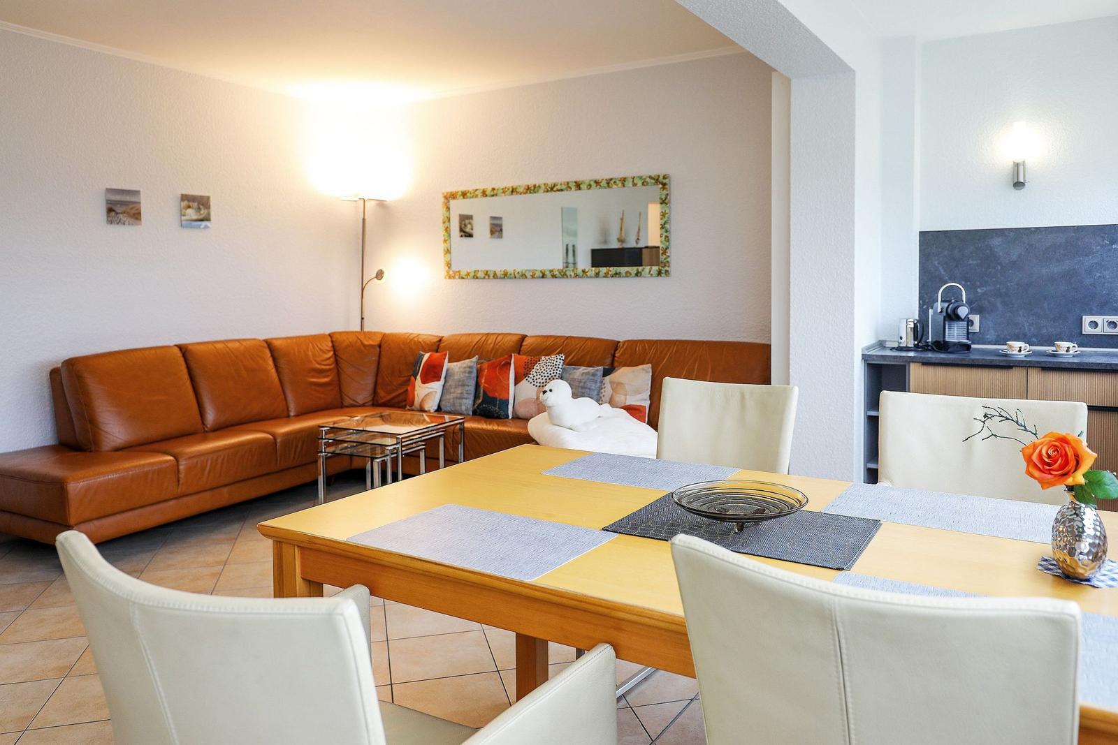 Wohn- und Essbereich mit braunem Sofa, Esstisch und Küchenzeile.