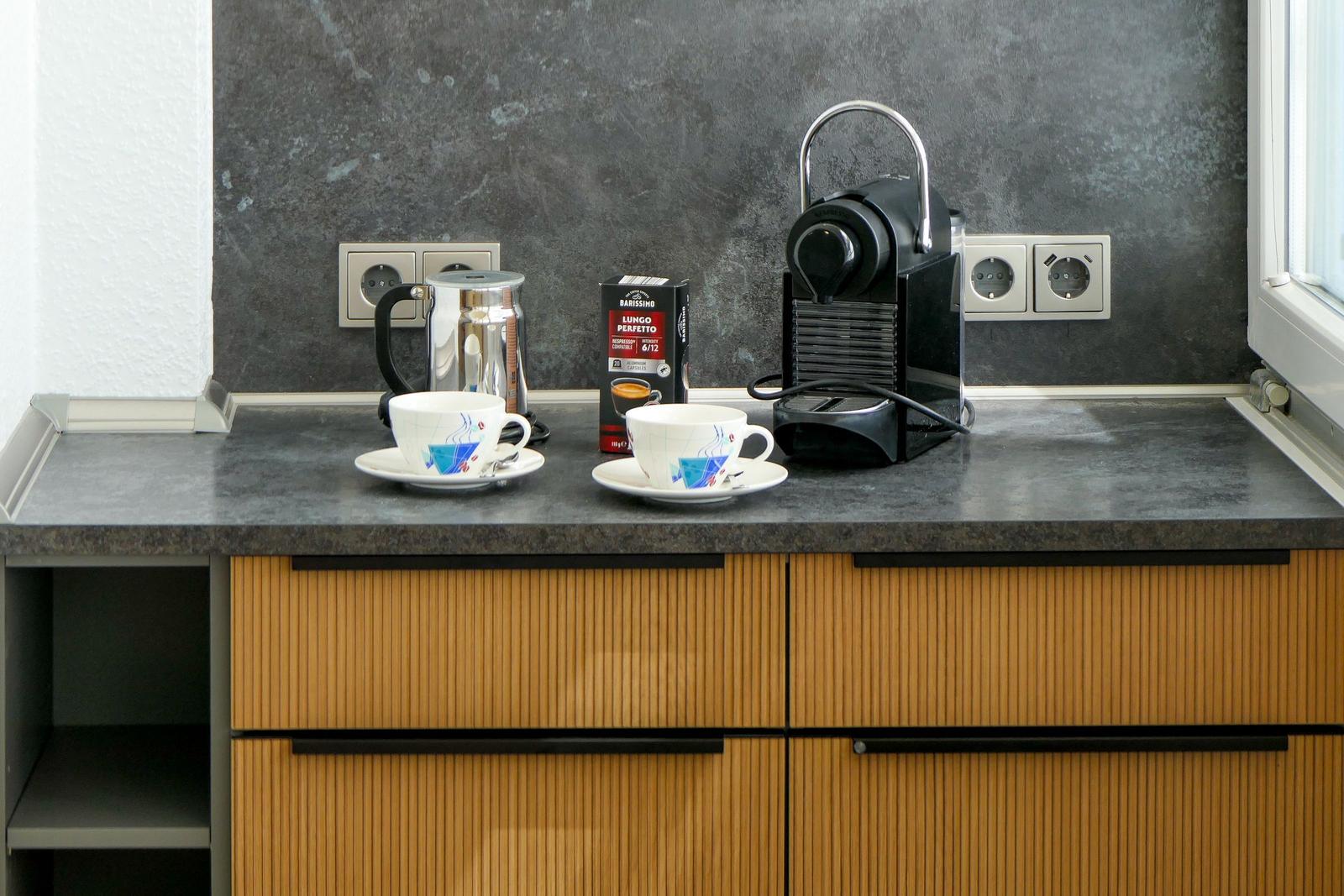 Küchenarbeitsplatte mit Kaffeemaschine, Kaffeetassen und Kaffeevorrat.