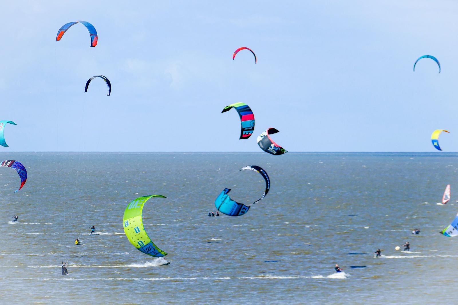 Viele Kitesurf-Parasiten fliegen über das Meer.