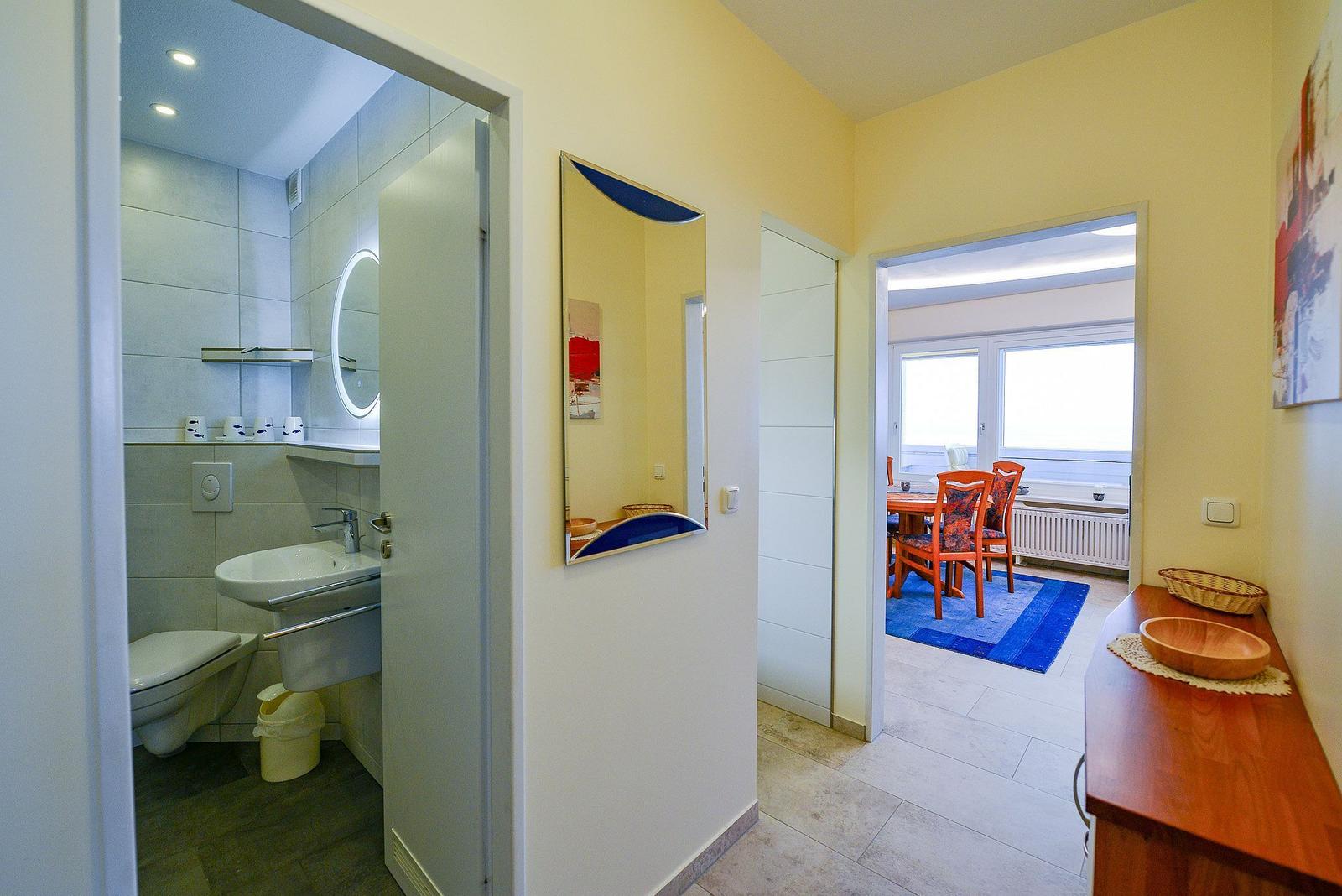 Flur mit Blick in Bad und Esszimmer mit Tisch, Stühlen und Fenster