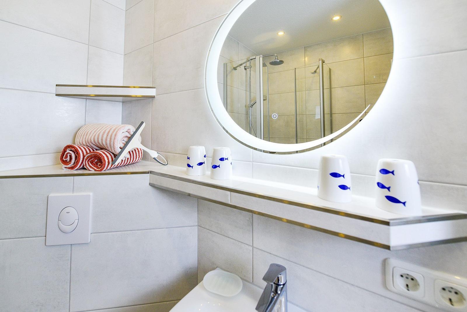 Badezimmer mit runden Spiegel, Handtuch und Waschbecken.