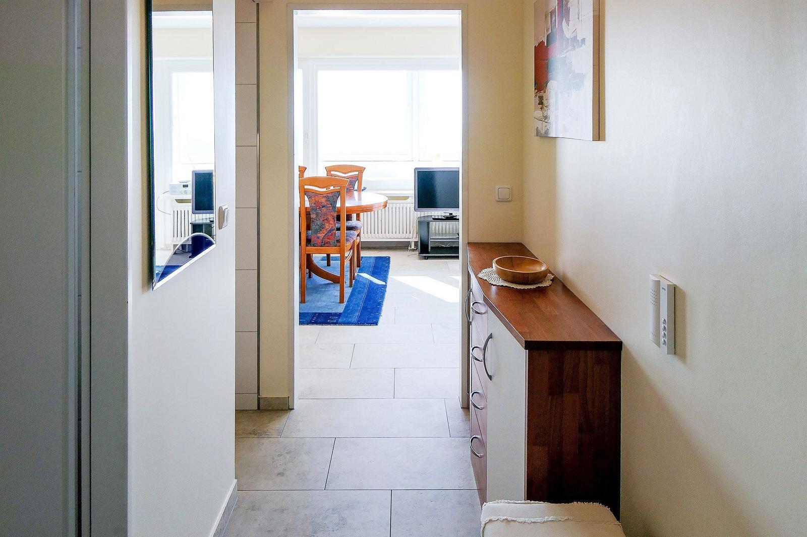 Flur mit Schrank und Blick in Esszimmer mit Tisch, Stühlen und TV.