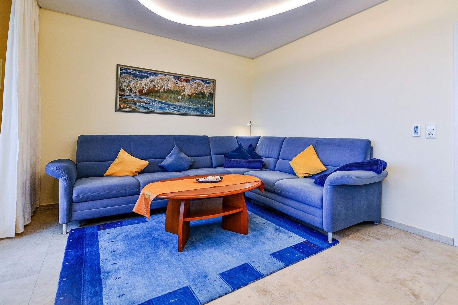 Blauer Sofa mit Kissen, Holztisch und Teppich im Wohnzimmer.