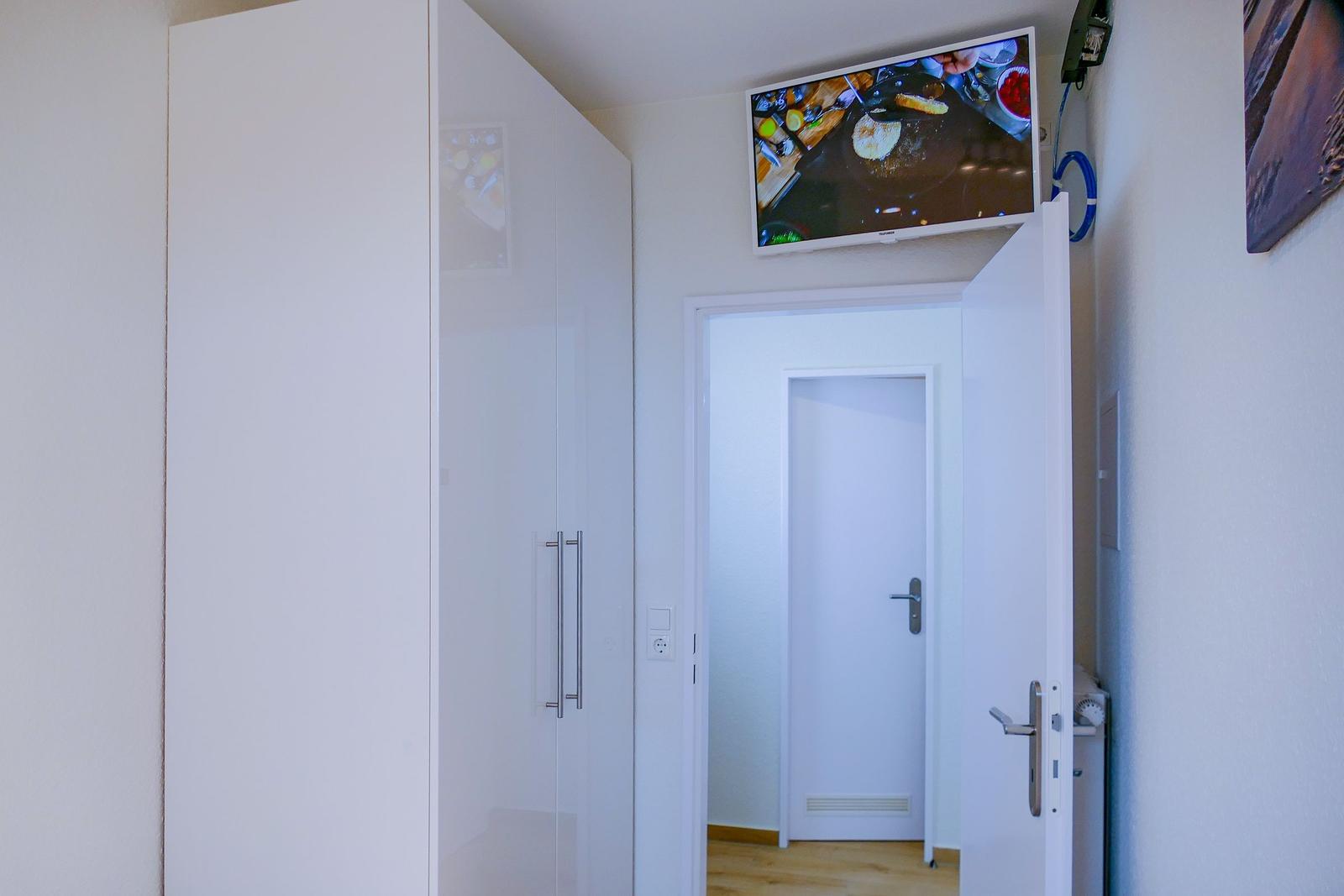 Schlafzimmer mit Kleiderschrank und Fernseher an der Wand.
