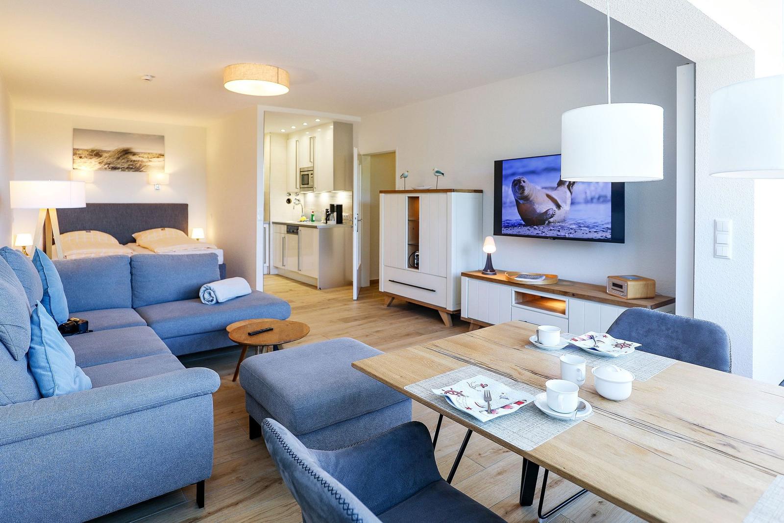 Wohnung mit Essbereich, Wohnbereich und Schlafzimmer. Fernseher, Couch und Esstisch sichtbar.