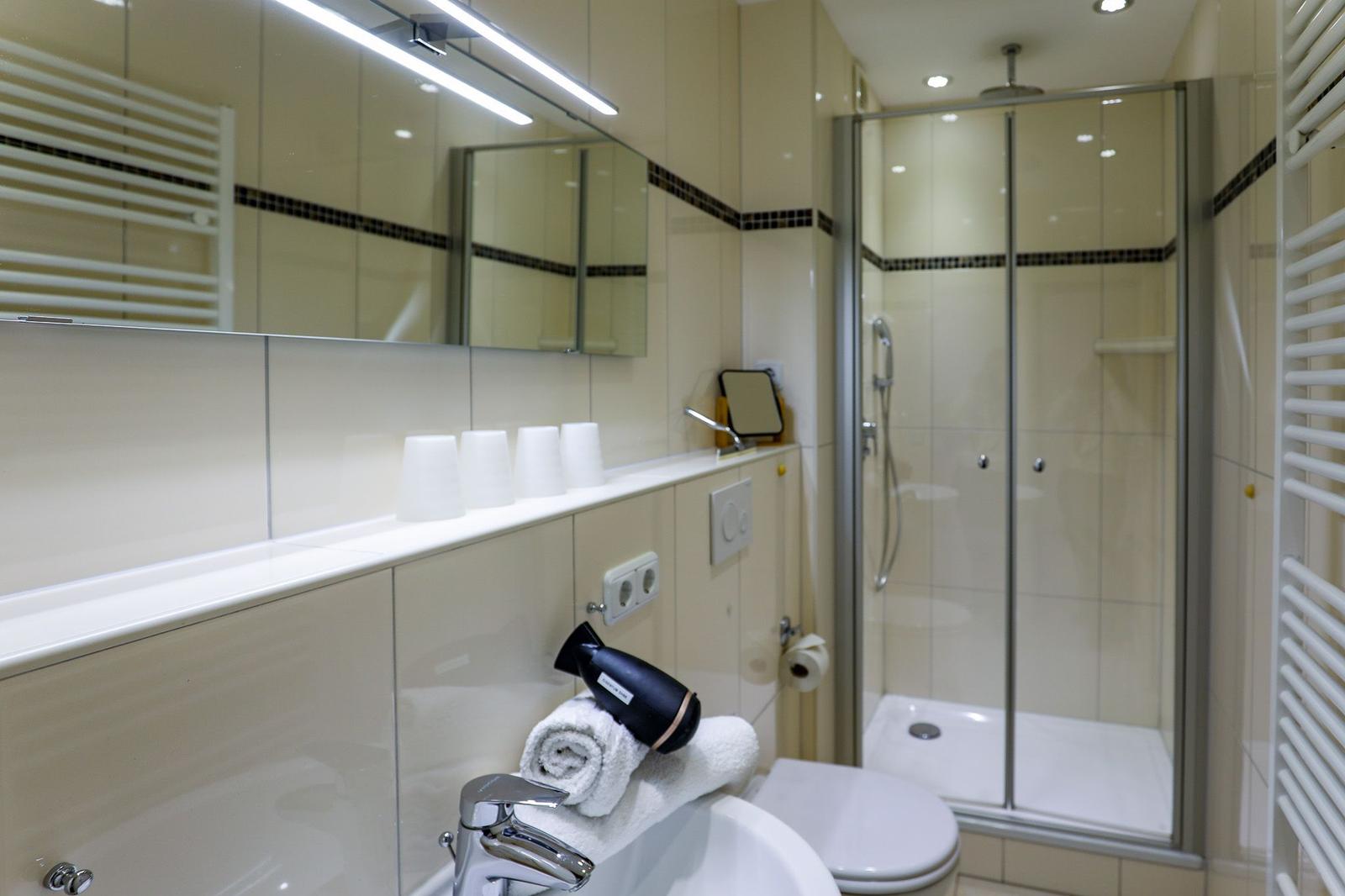 Badezimmer mit Dusche, Waschbecken und Spiegel.