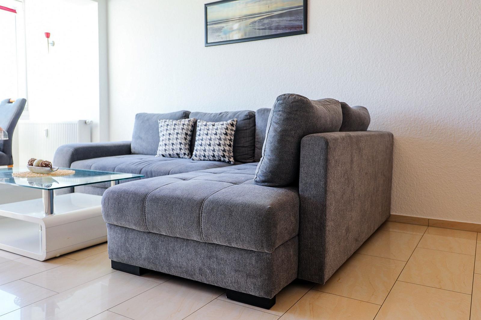 Graße Sofa mit Kissen und Glas-Tisch im Wohnzimmer.