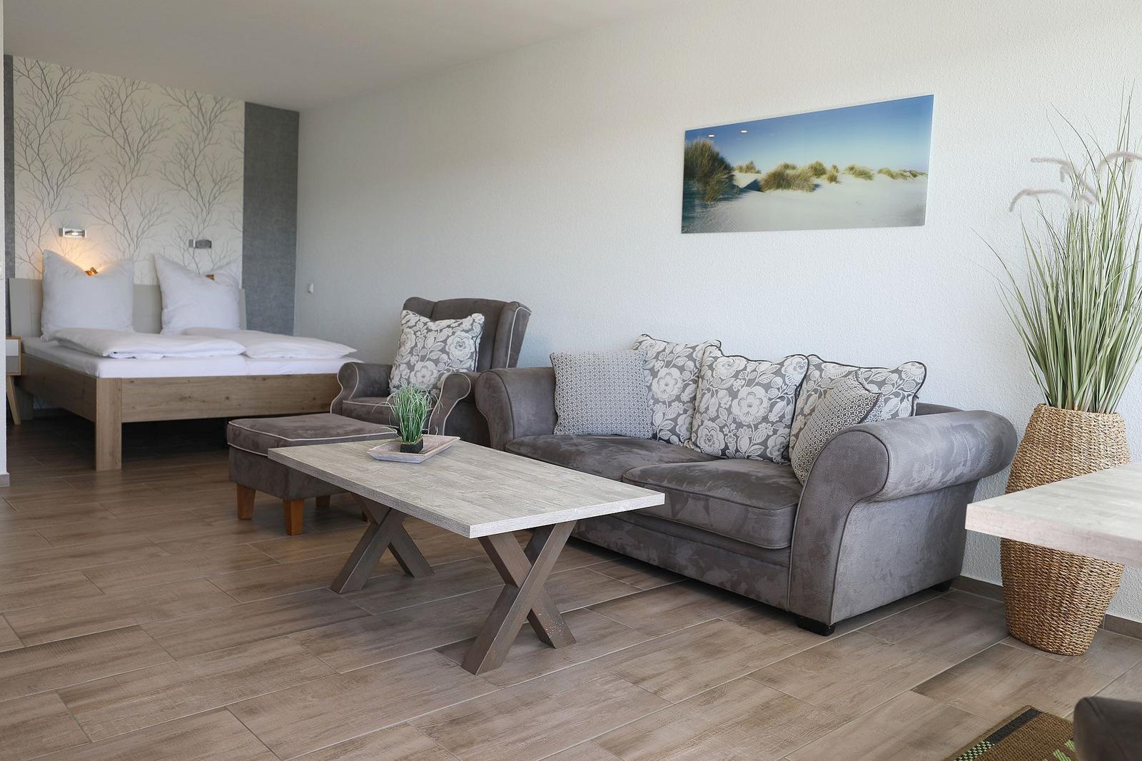 Wohnbereich mit Sofa, Couchtisch und Bett im Hintergrund.