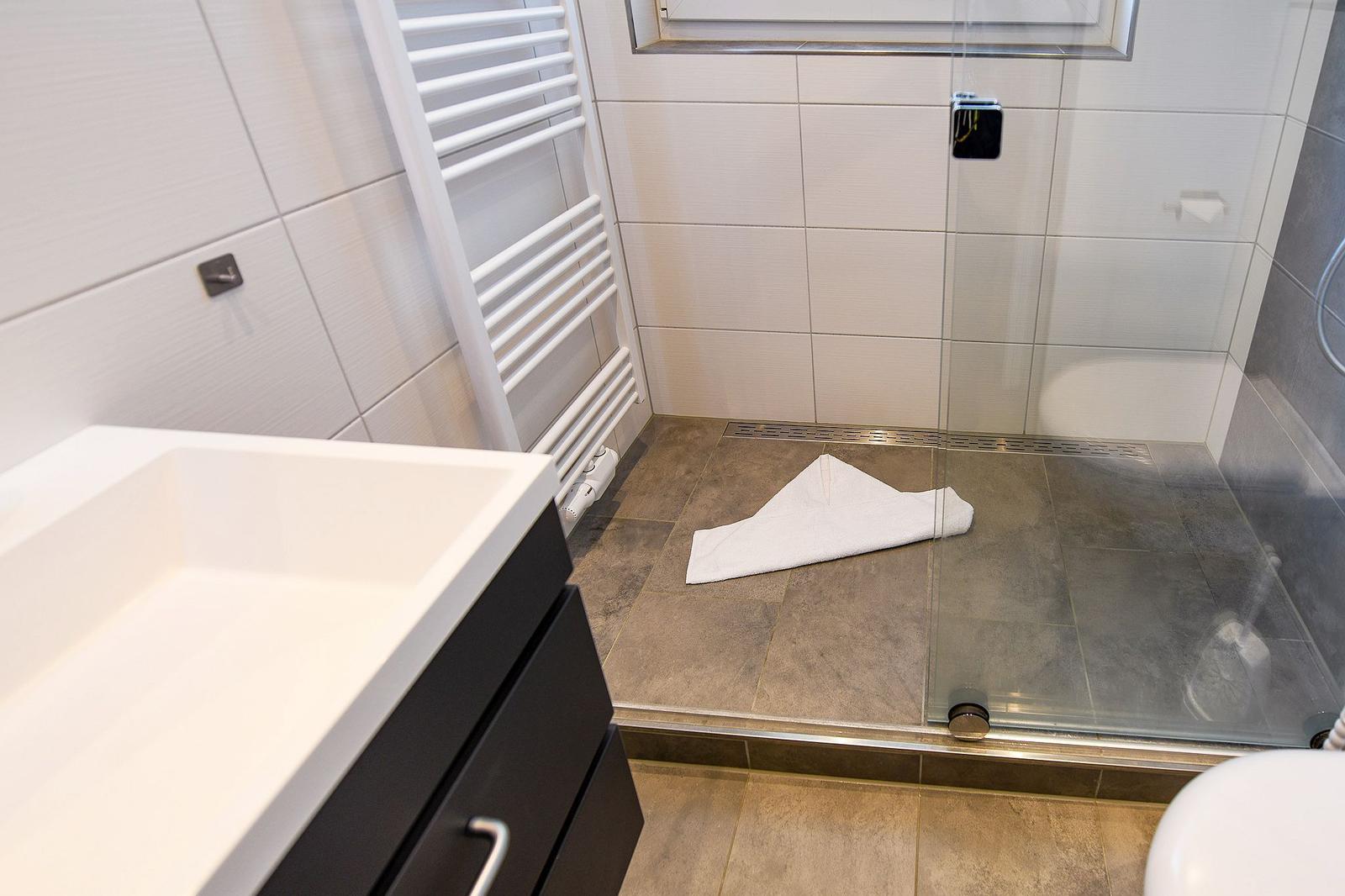 Bad mit Dusche, Waschbecken und Heizkörper