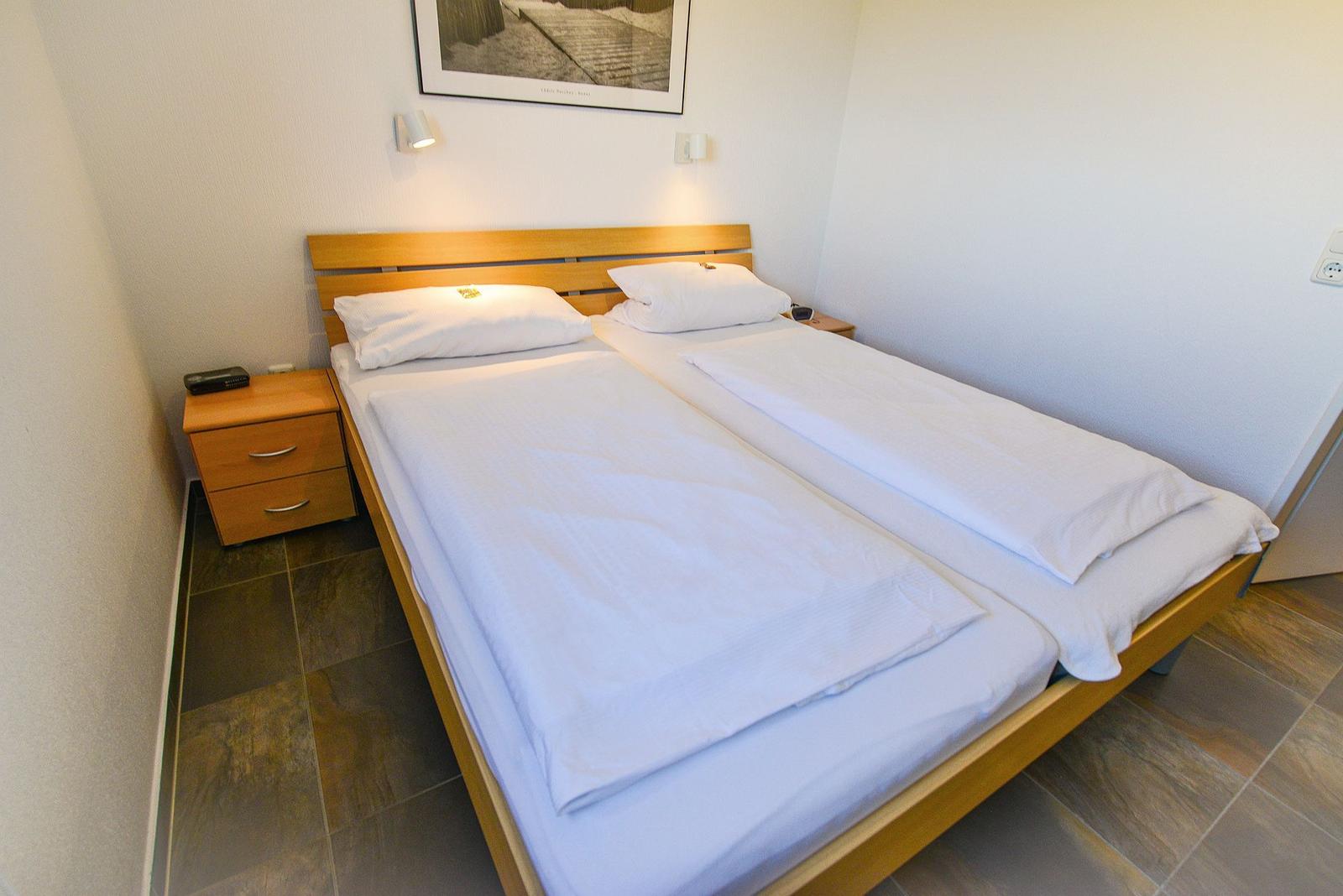 Schlafzimmer mit Doppelbett, Nachttisch und Wandbild