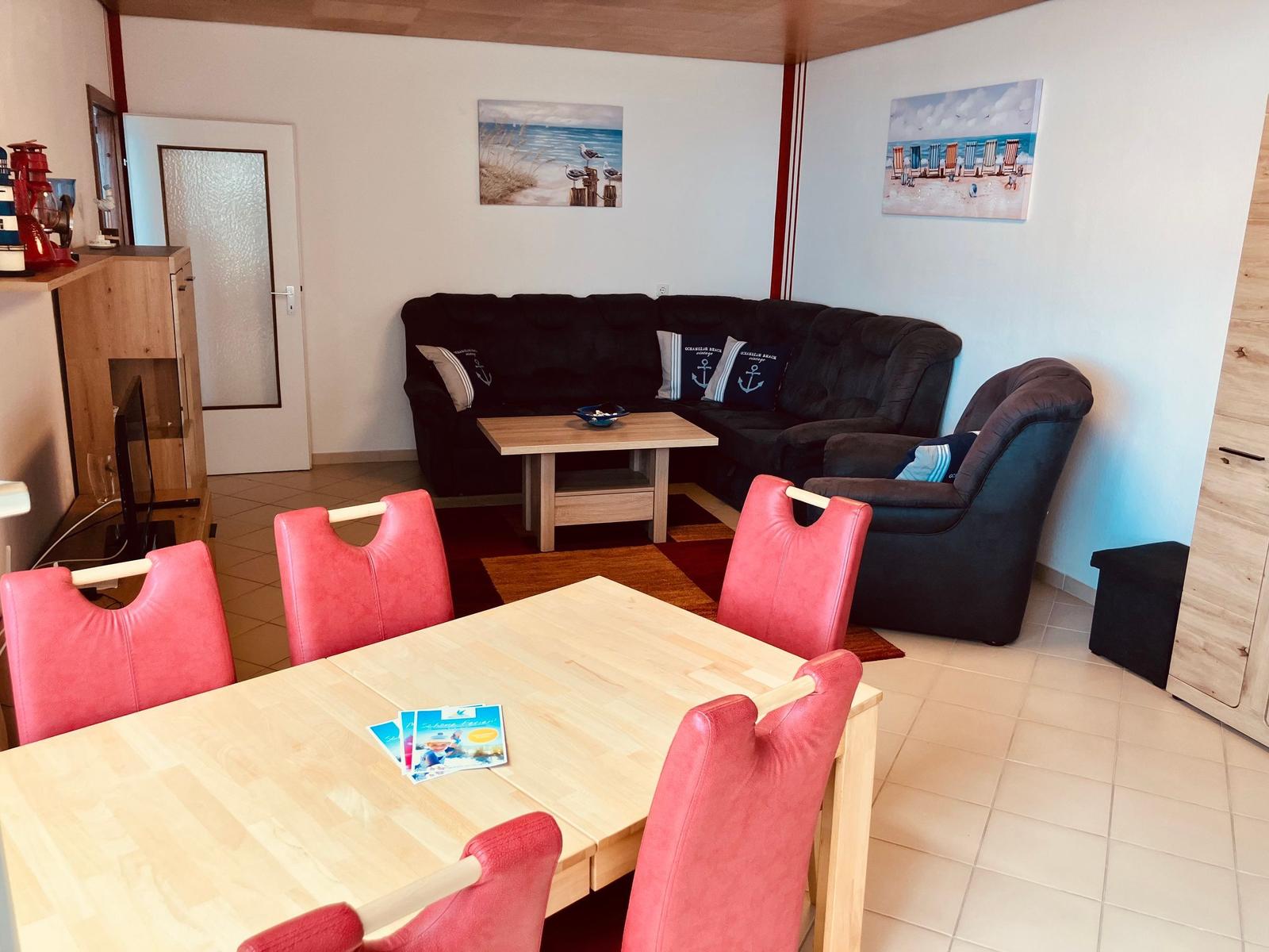 Esszimmer mit roten Stühlen und Wohnbereich mit Sofa und Kissen.