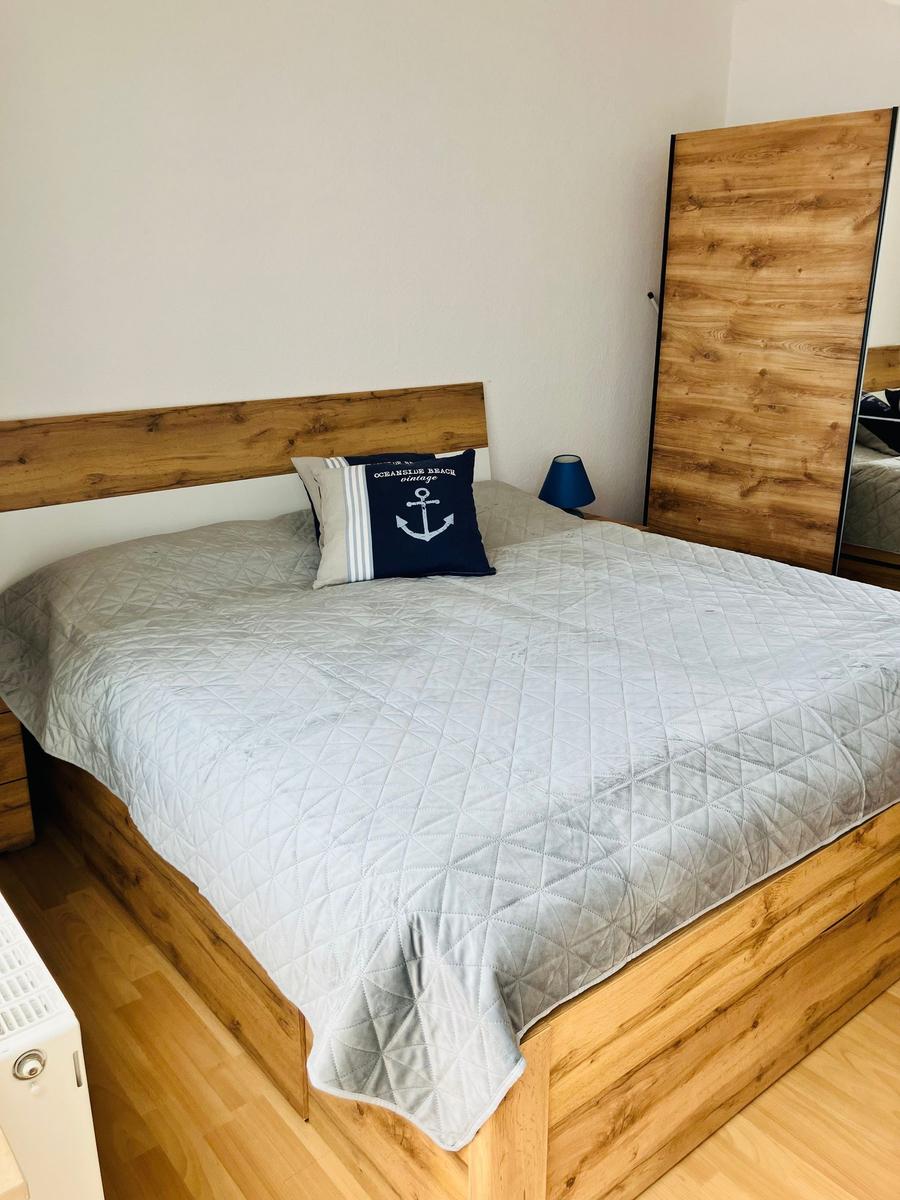 Schlafzimmer mit Holzbett, grauer Decke und Spiegelwand.