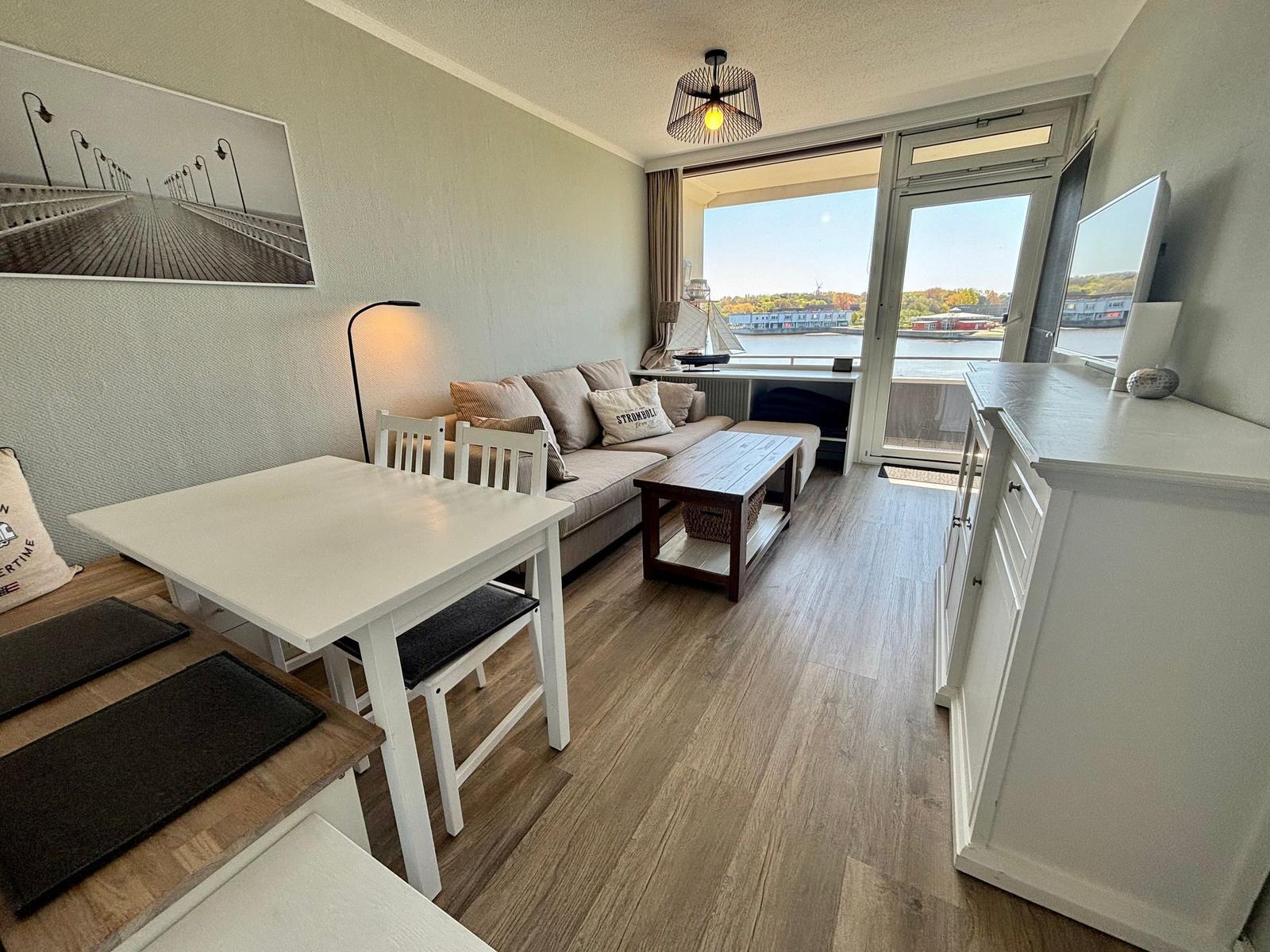 Wohnzimmer mit Sofa, Esstisch und Blick auf den Fluss.