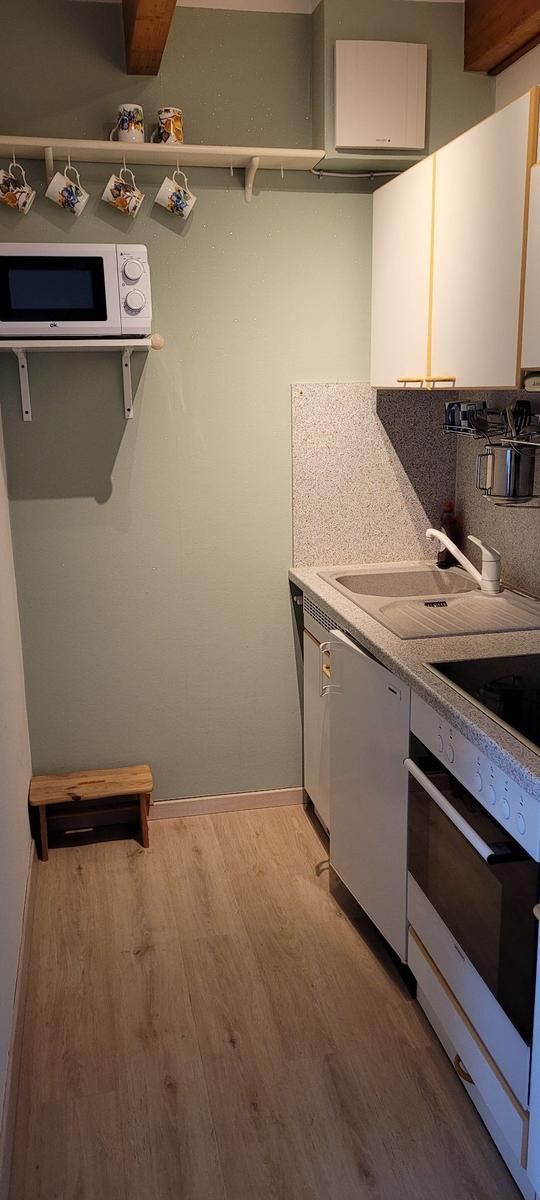Küche mit Spüle, Herd, Mikrowelle und Holzbank